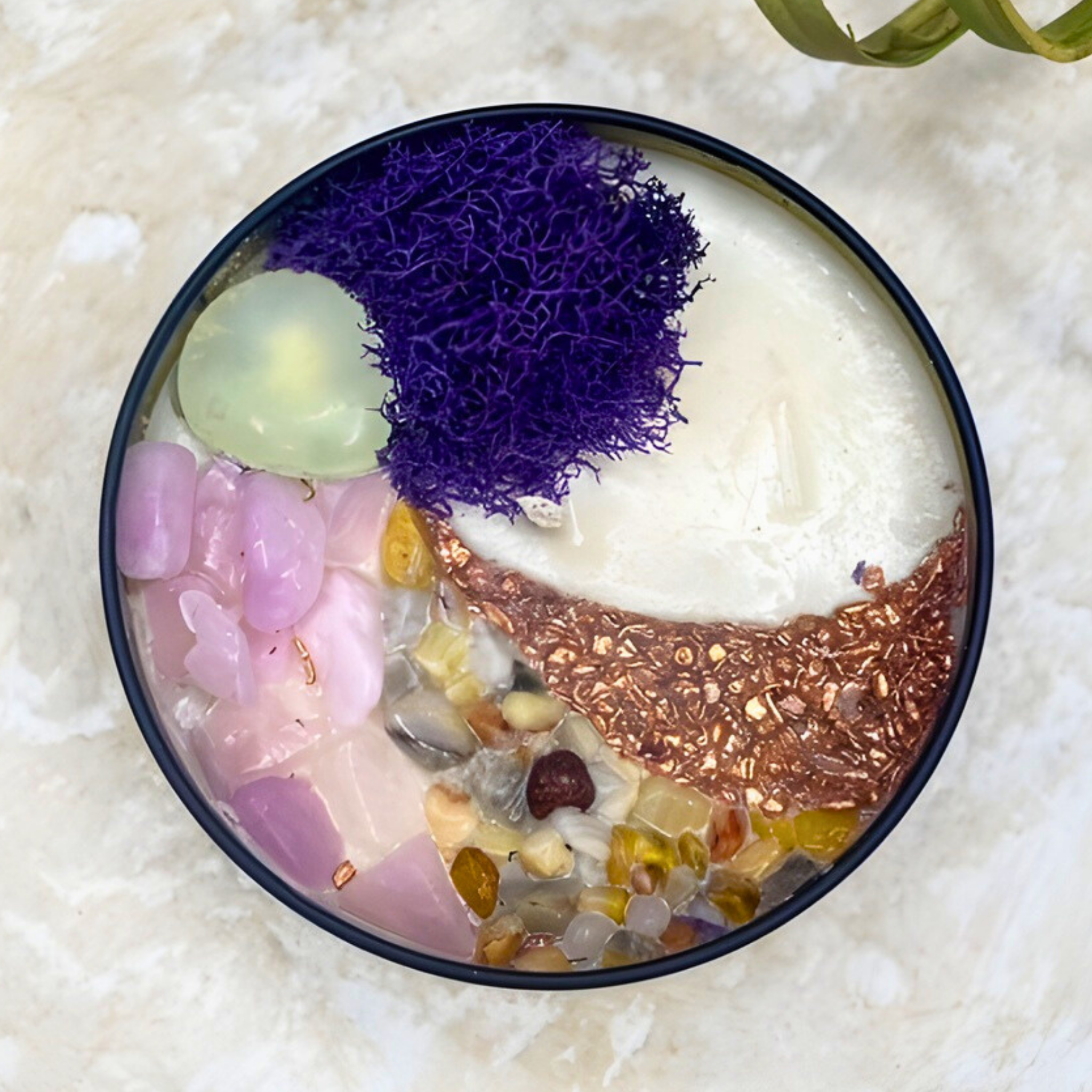 Decorative bowl with colorful stones and a purple moss-like substance on a textured surface