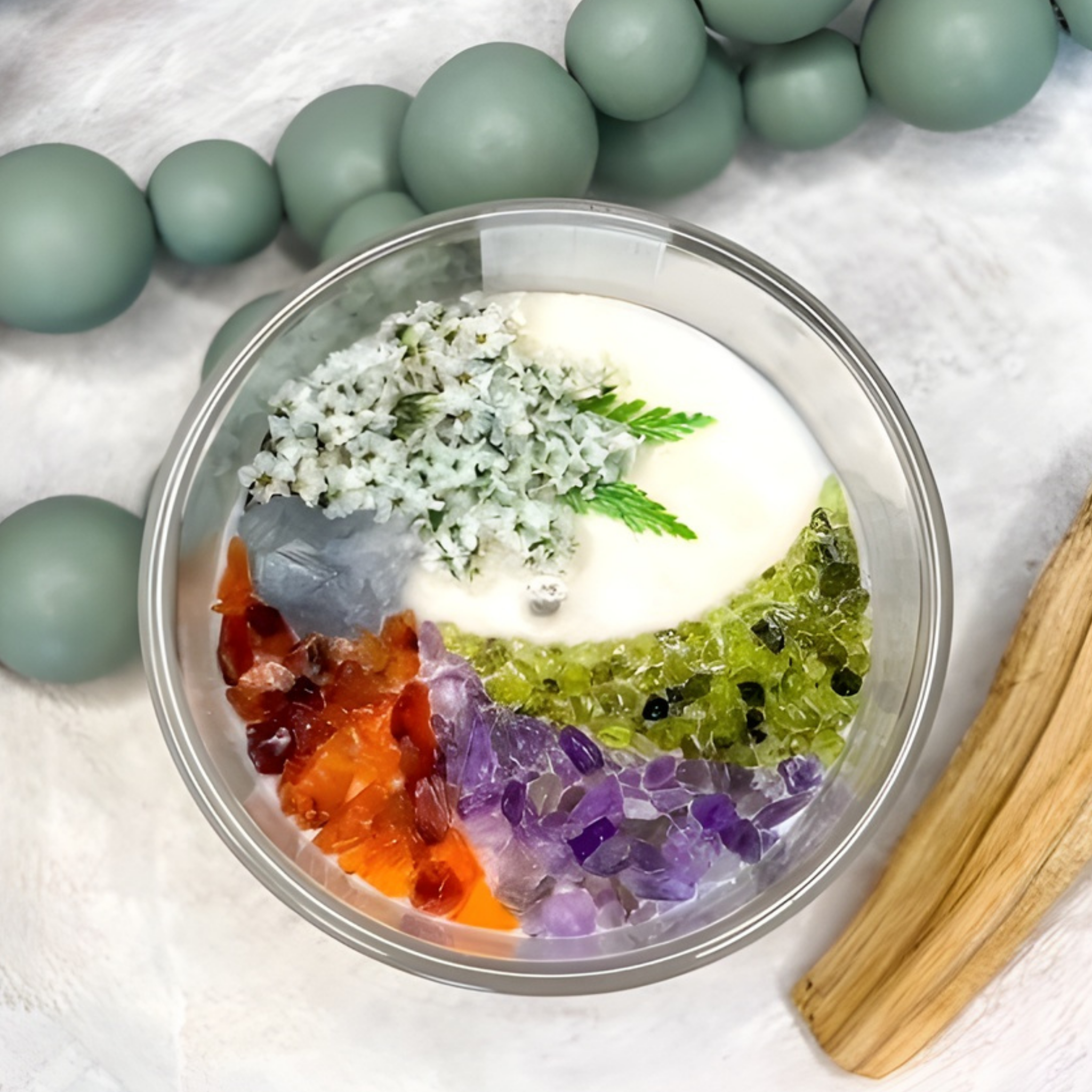 scented candle with flowers and crystals in clear jar with green beads