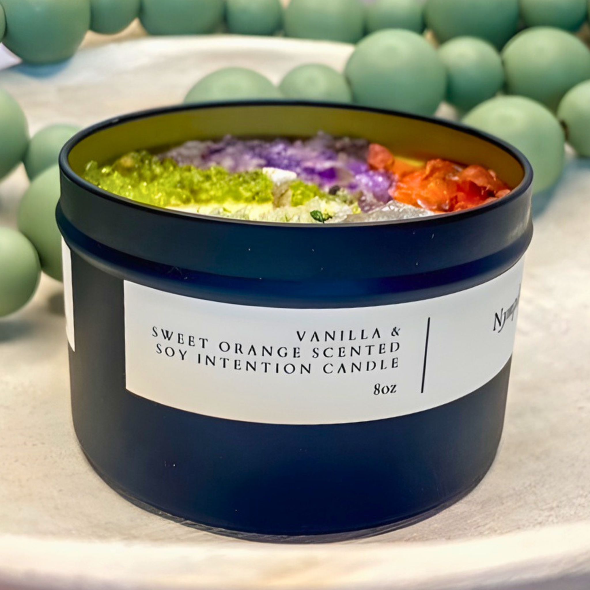 scented candle with flowers and crystals in black jar