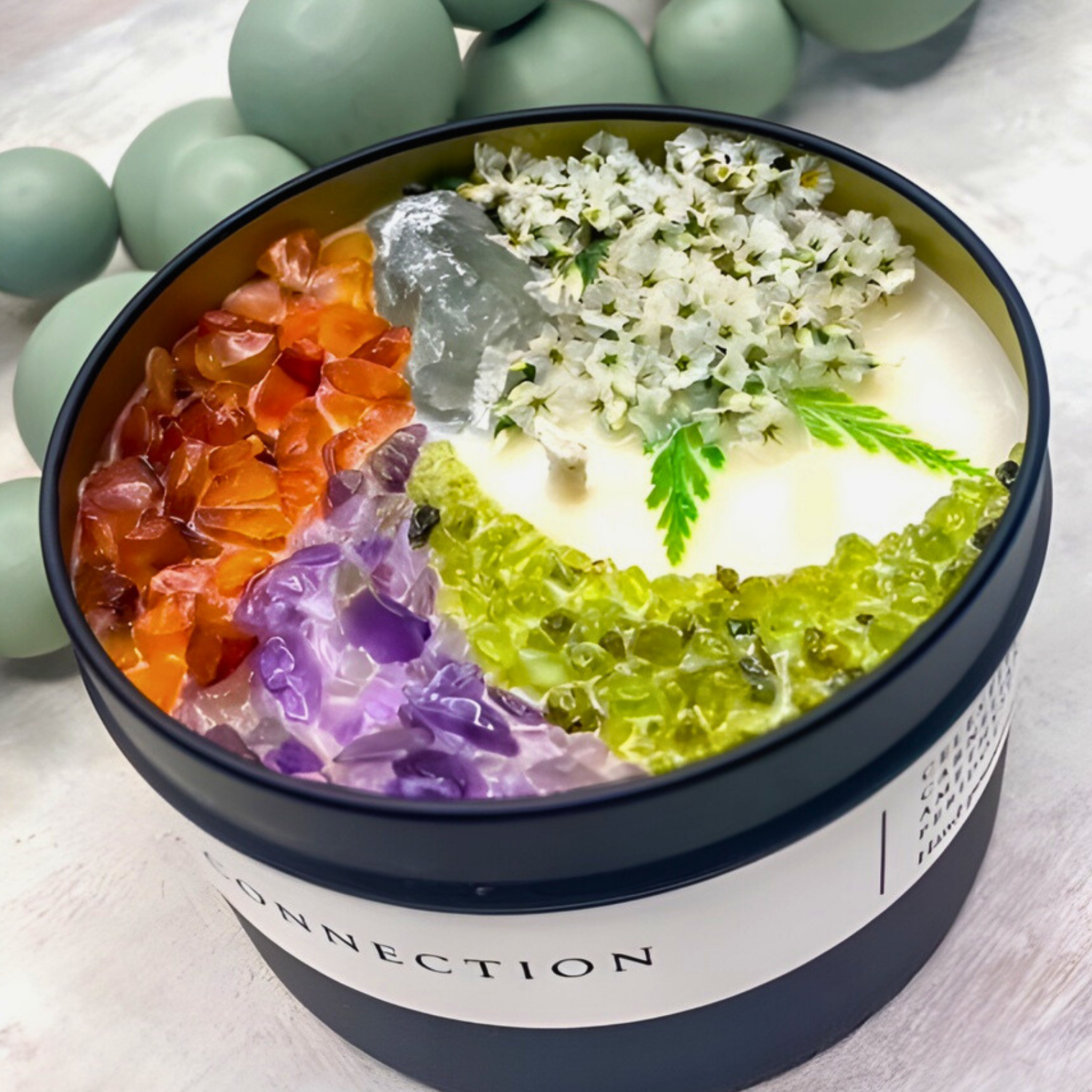 scented candle with flowers and crystals in black jar