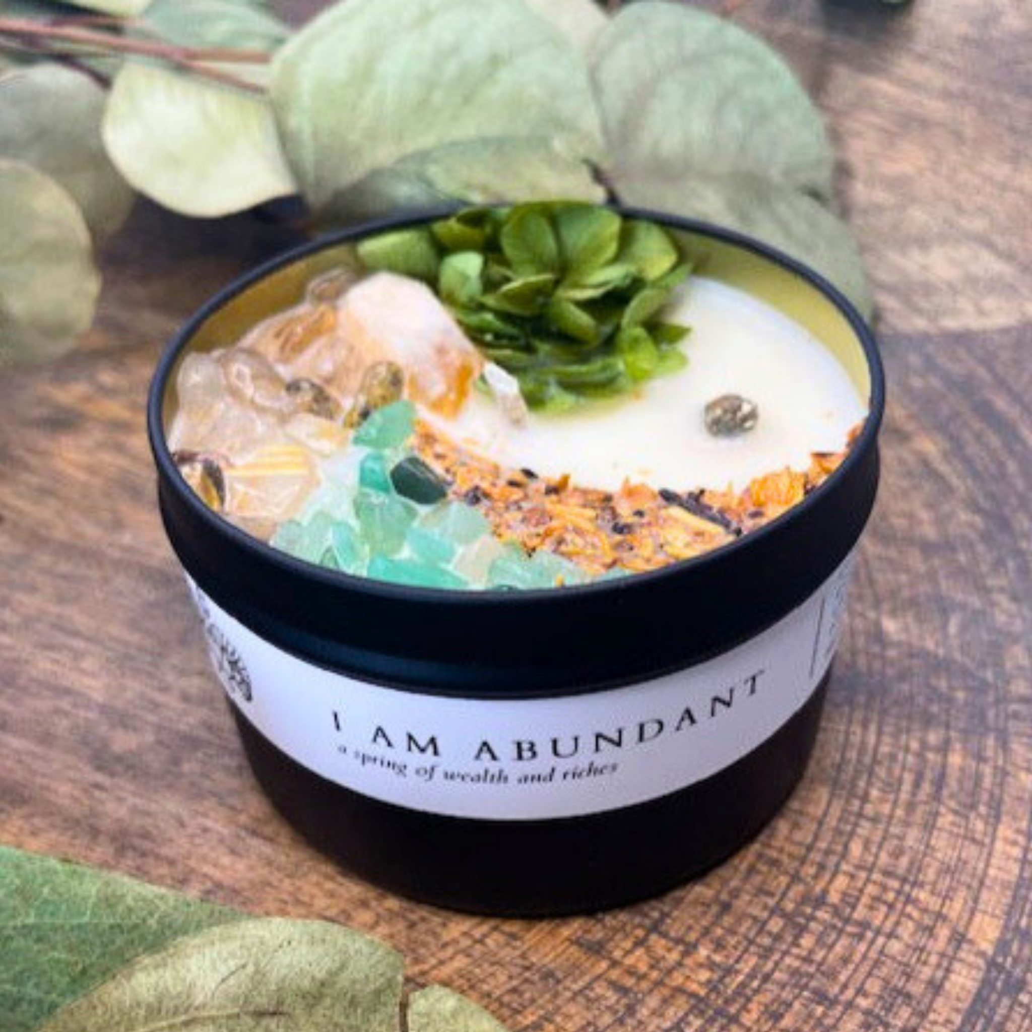 Candle in a black container with decorative elements on a wooden surface