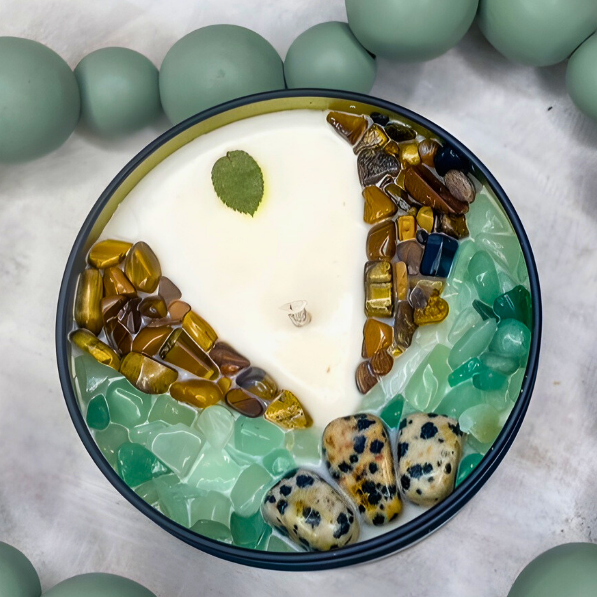 Decorative scented candle with stones and a leaf on a white background