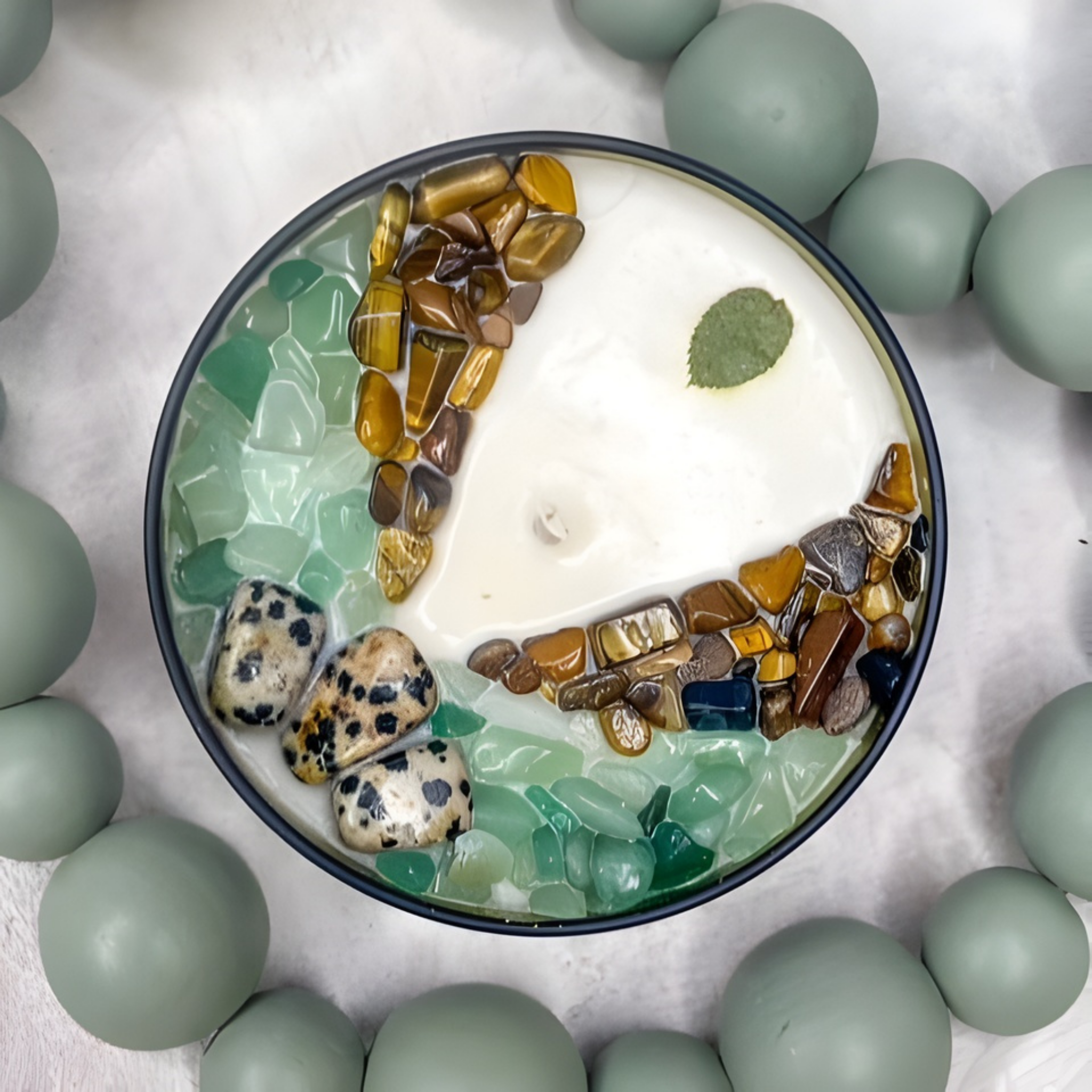 Decorative scented candle with pebbles arranged in a circular pattern on a light background