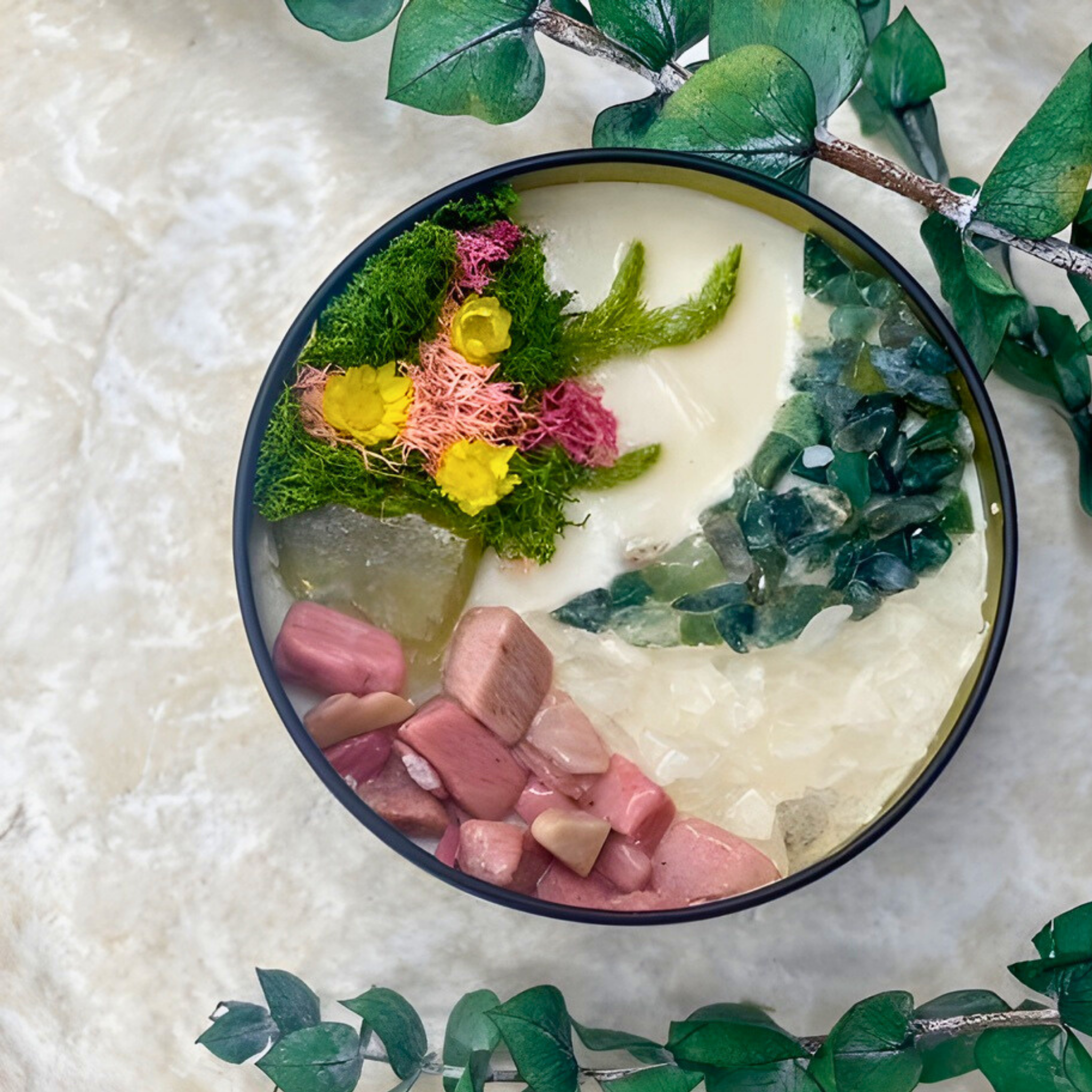 Bowl of dessert with pink and yellow flowers and green leaves on a textured surface.