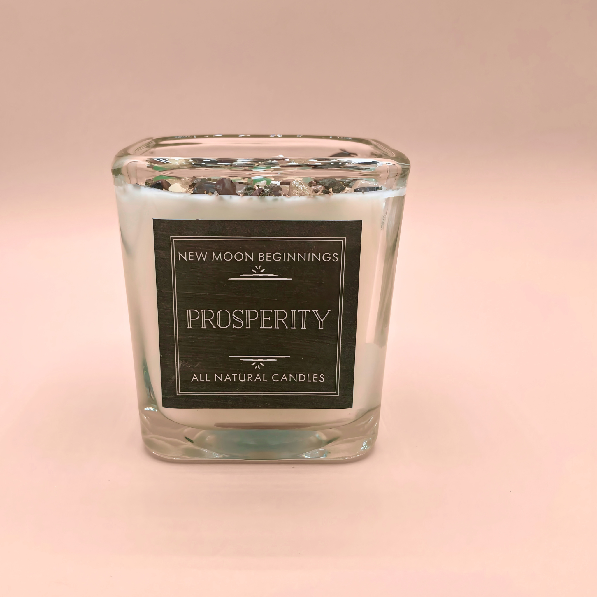 Clear glass candle with a black label on a pink background
