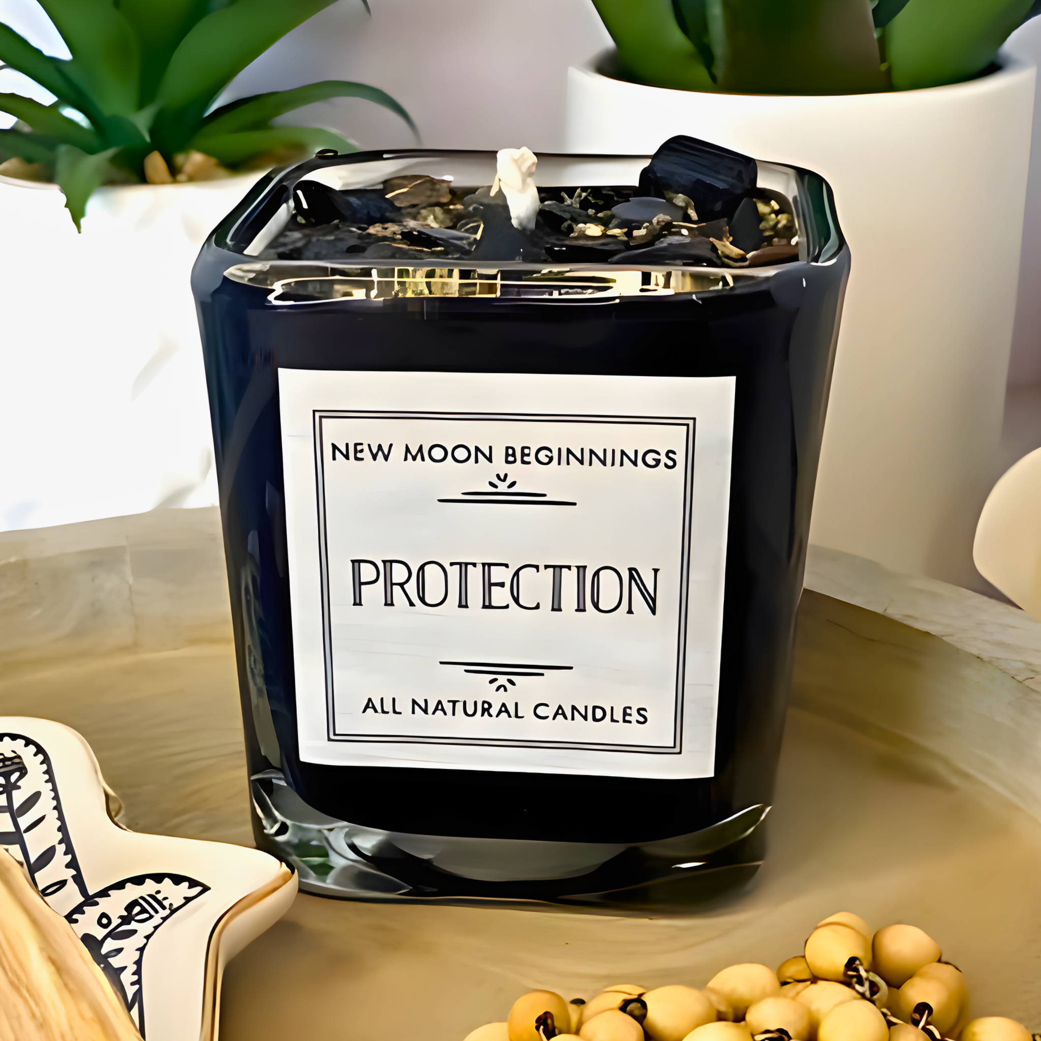Black candle labeled 'Protection' by 'New Moon Beginnings' on a surface with plants in the background.