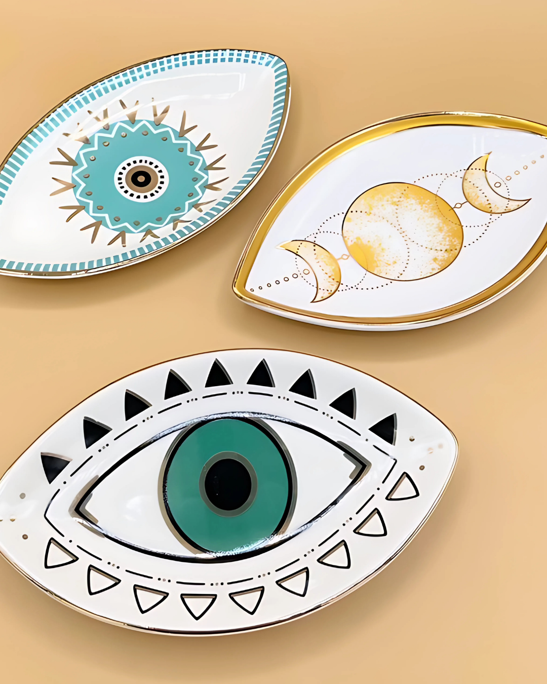 Three decorative plates with eye and celestial designs on a beige background
