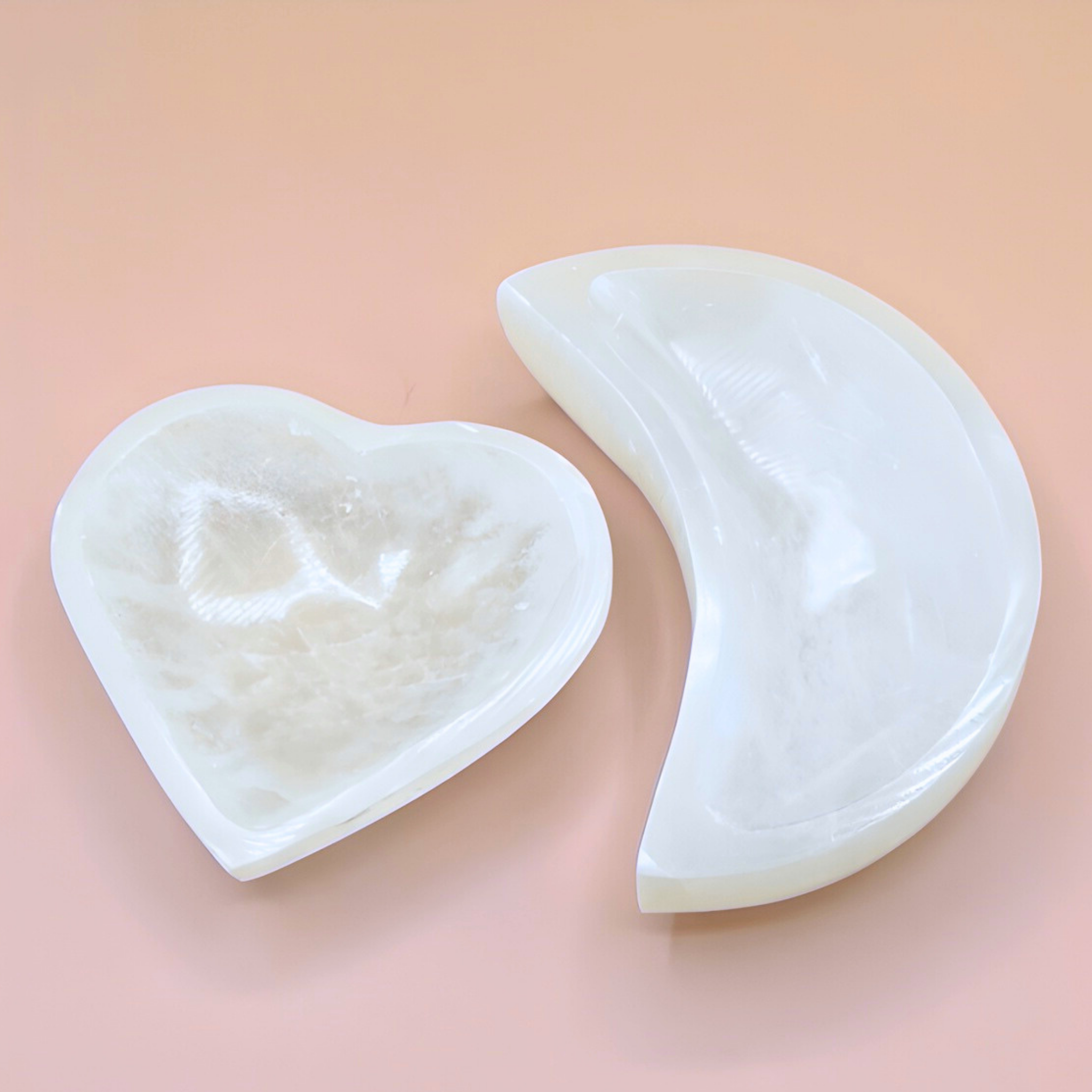Heart-shaped and crescent-shaped white soap bars on a pink background