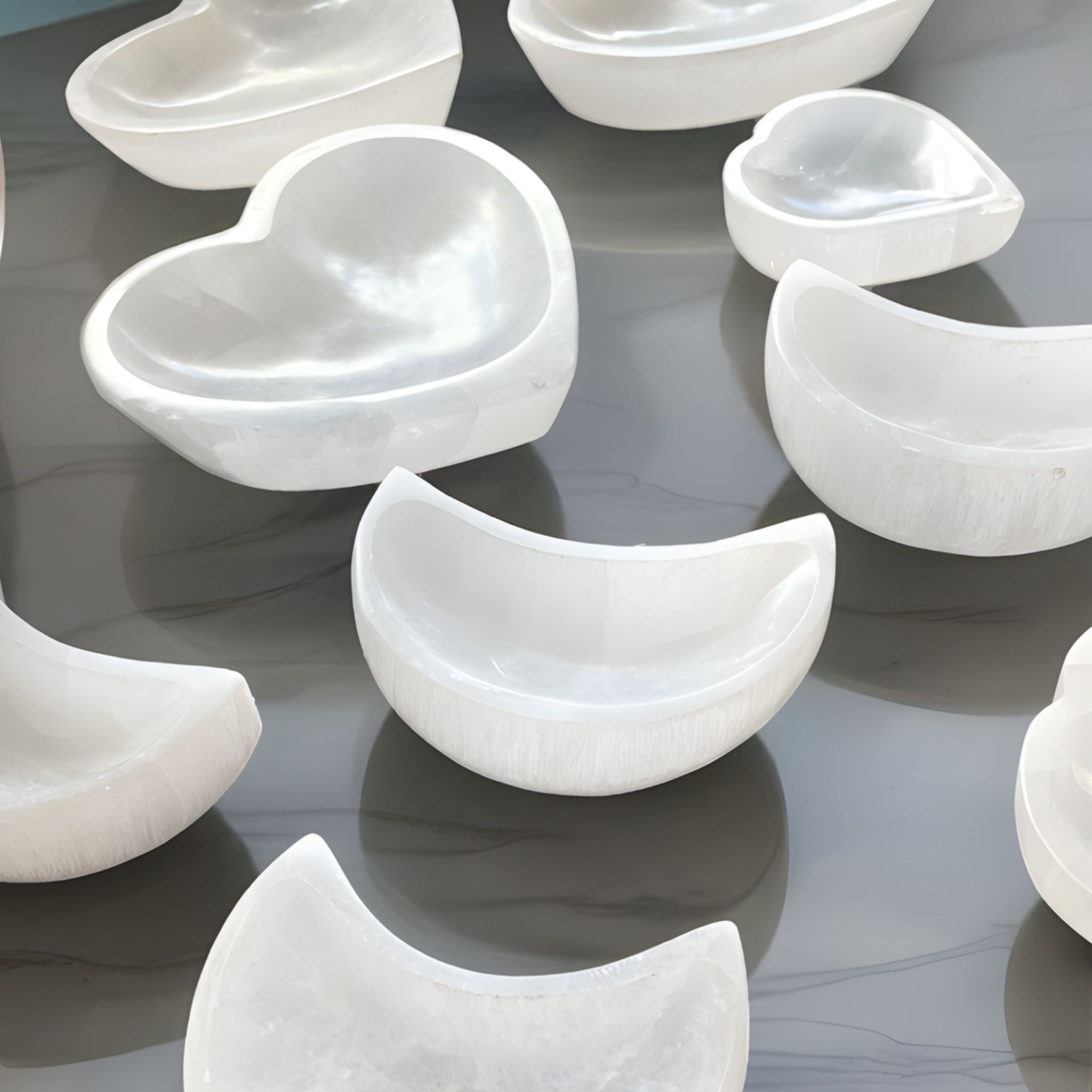 White marble bowls of various shapes on a reflective surface