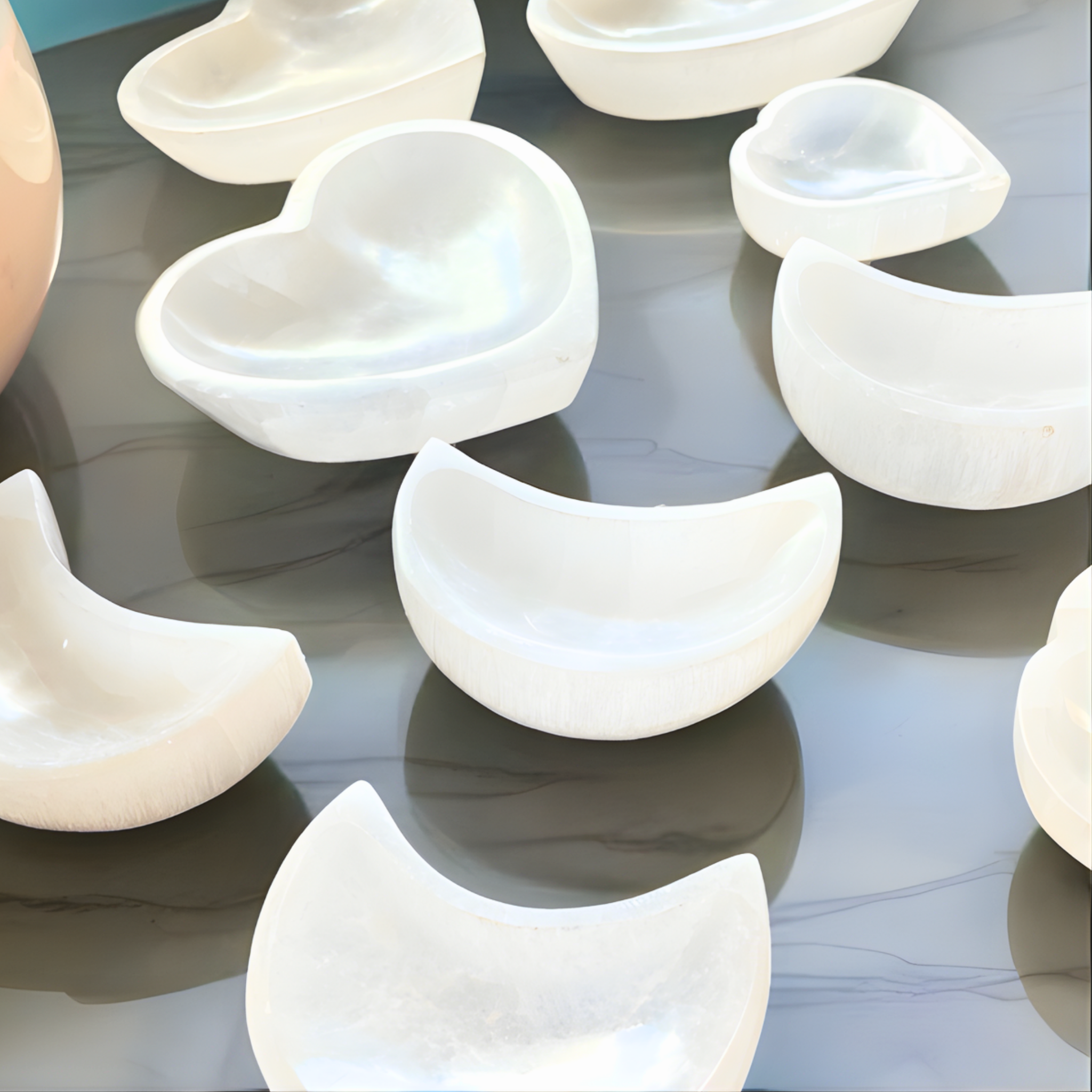 White selenite crystal charging bowls on a reflective surface