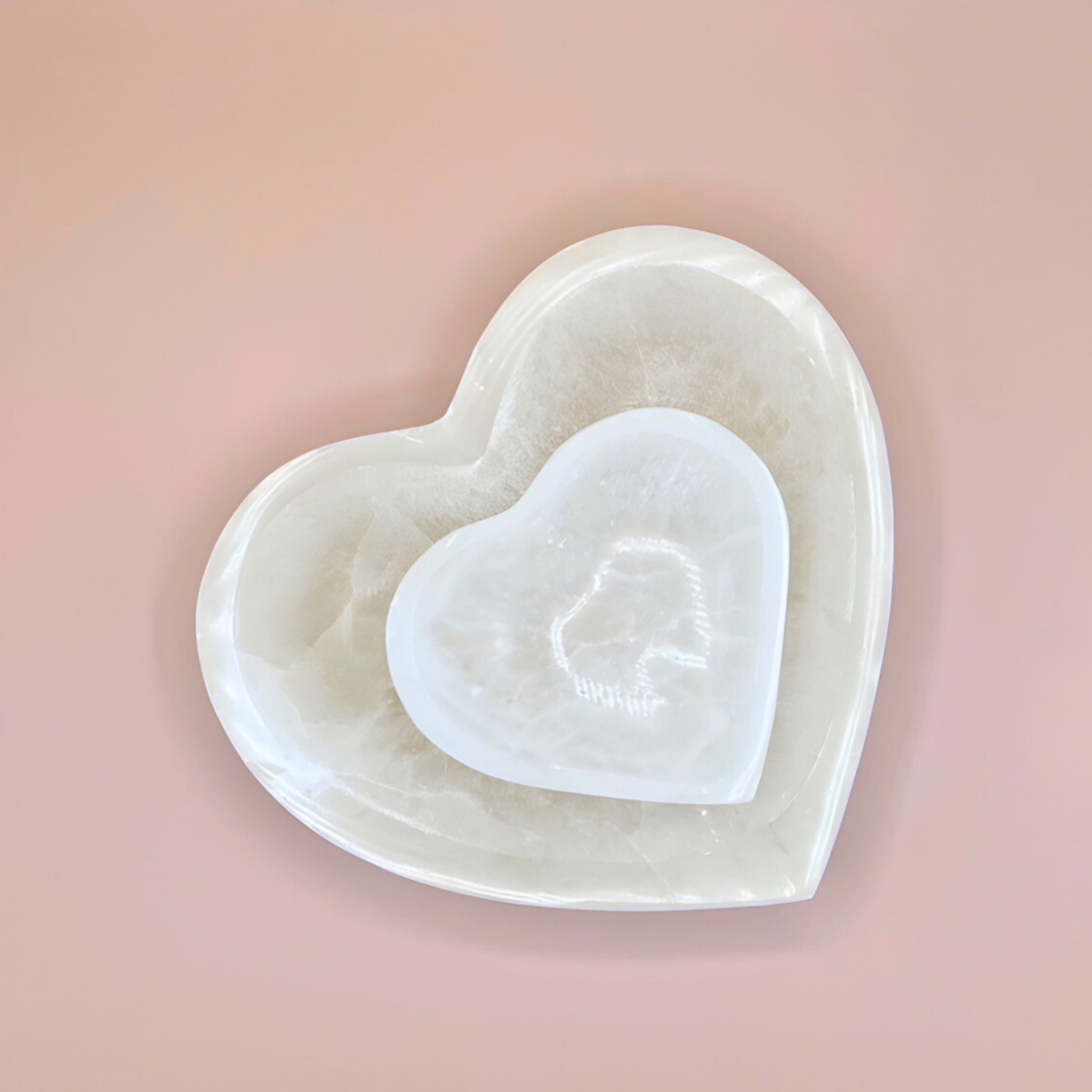 Heart-shaped white ceramic dish with a smaller heart inside on a pink background