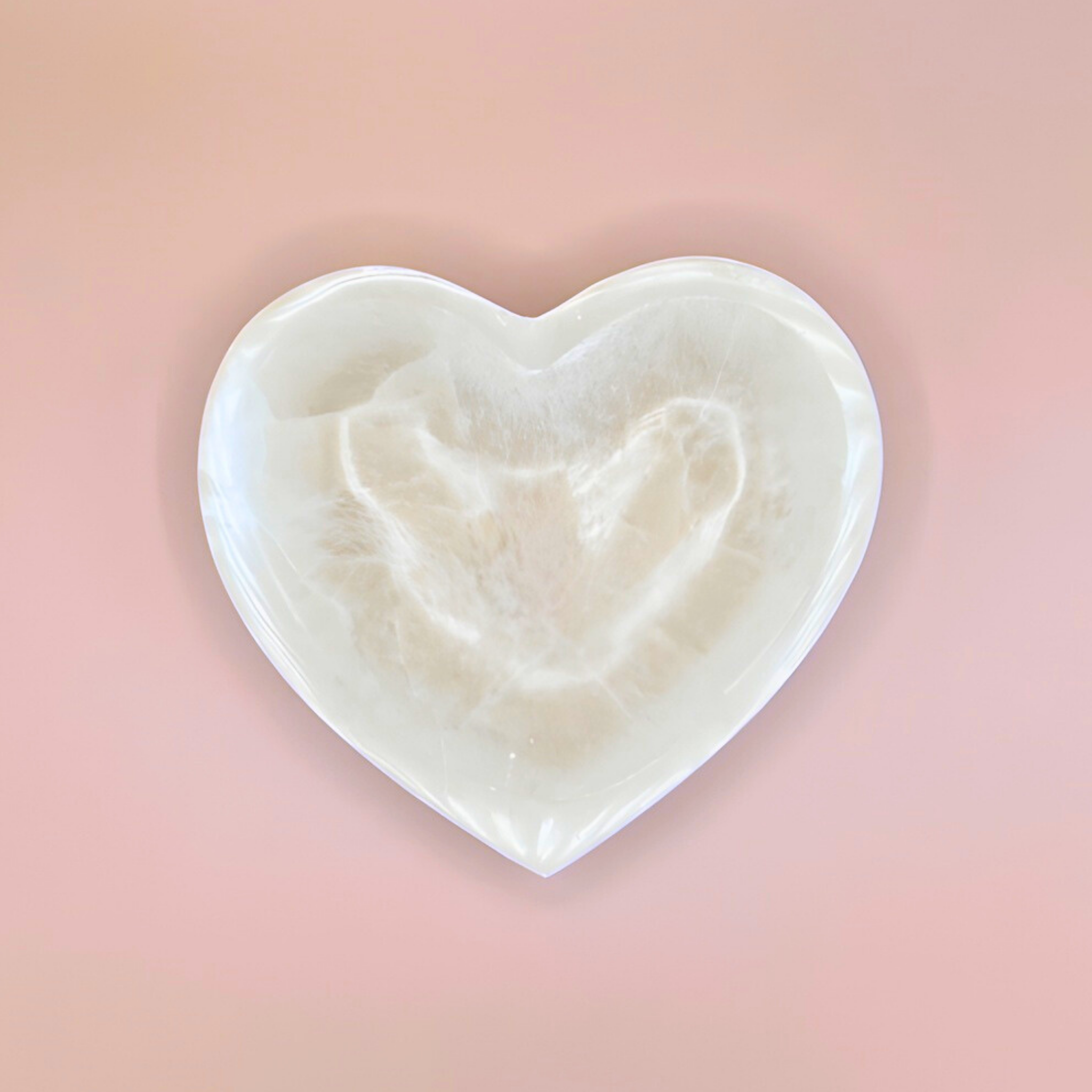 Heart-shaped object with a textured surface on a pink background