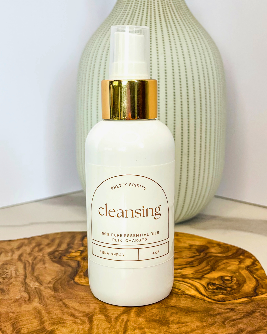 White bottle with gold cap labeled 'cleansing' on a wooden surface with a textured background