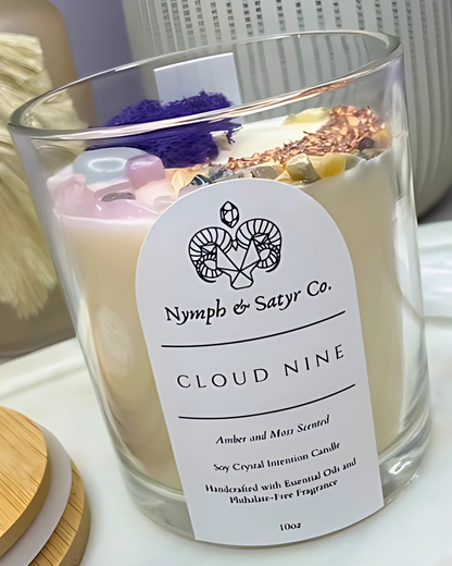 Candle labeled 'Nymph & Satyr Co. Cloud Nine' with decorative elements inside the glass.