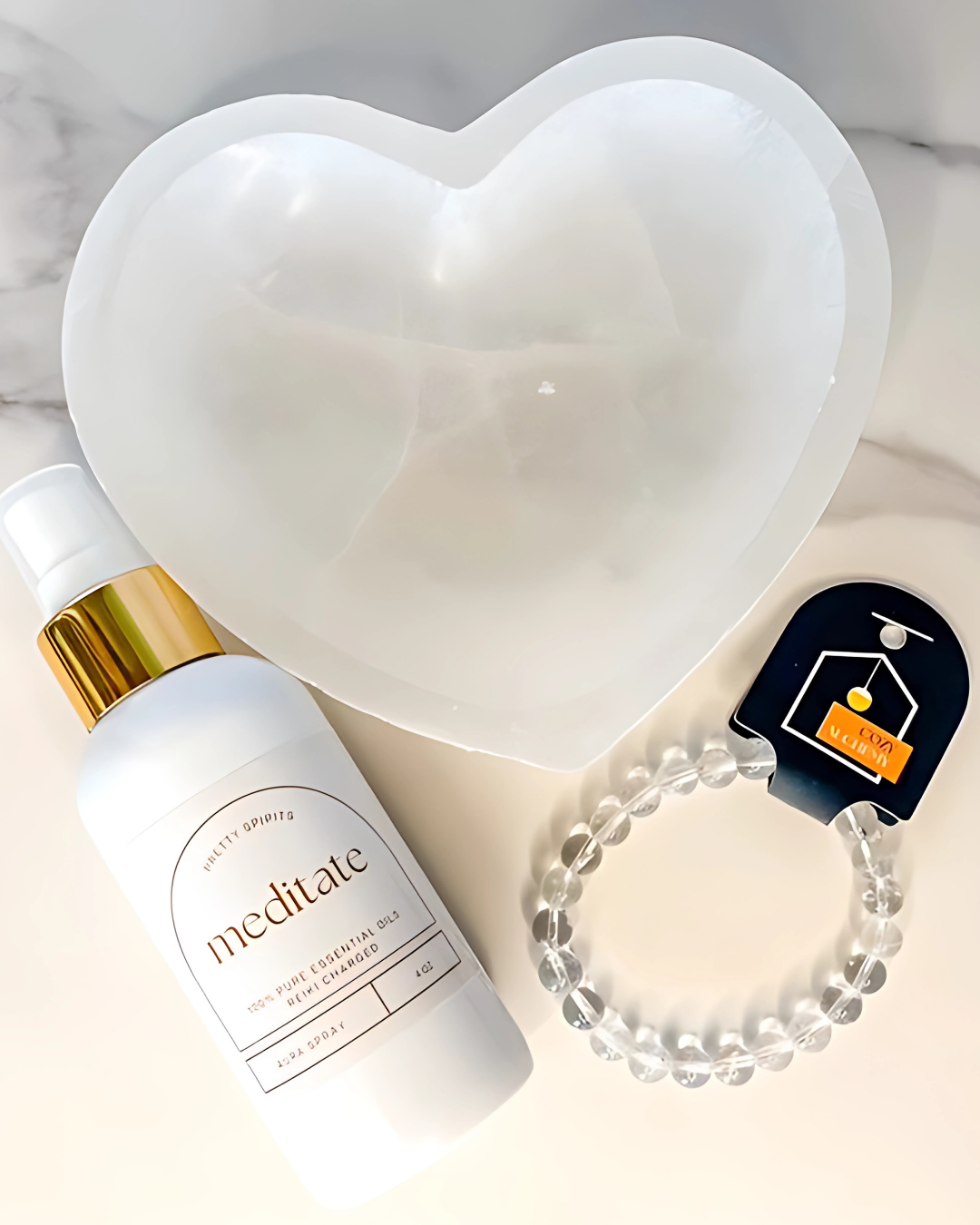White bottle labeled 'meditate', clear bracelet, and black device on a light gray background