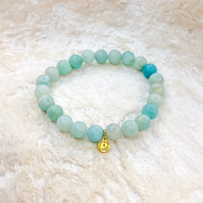 Beaded bracelet with a gold charm on a textured beige surface