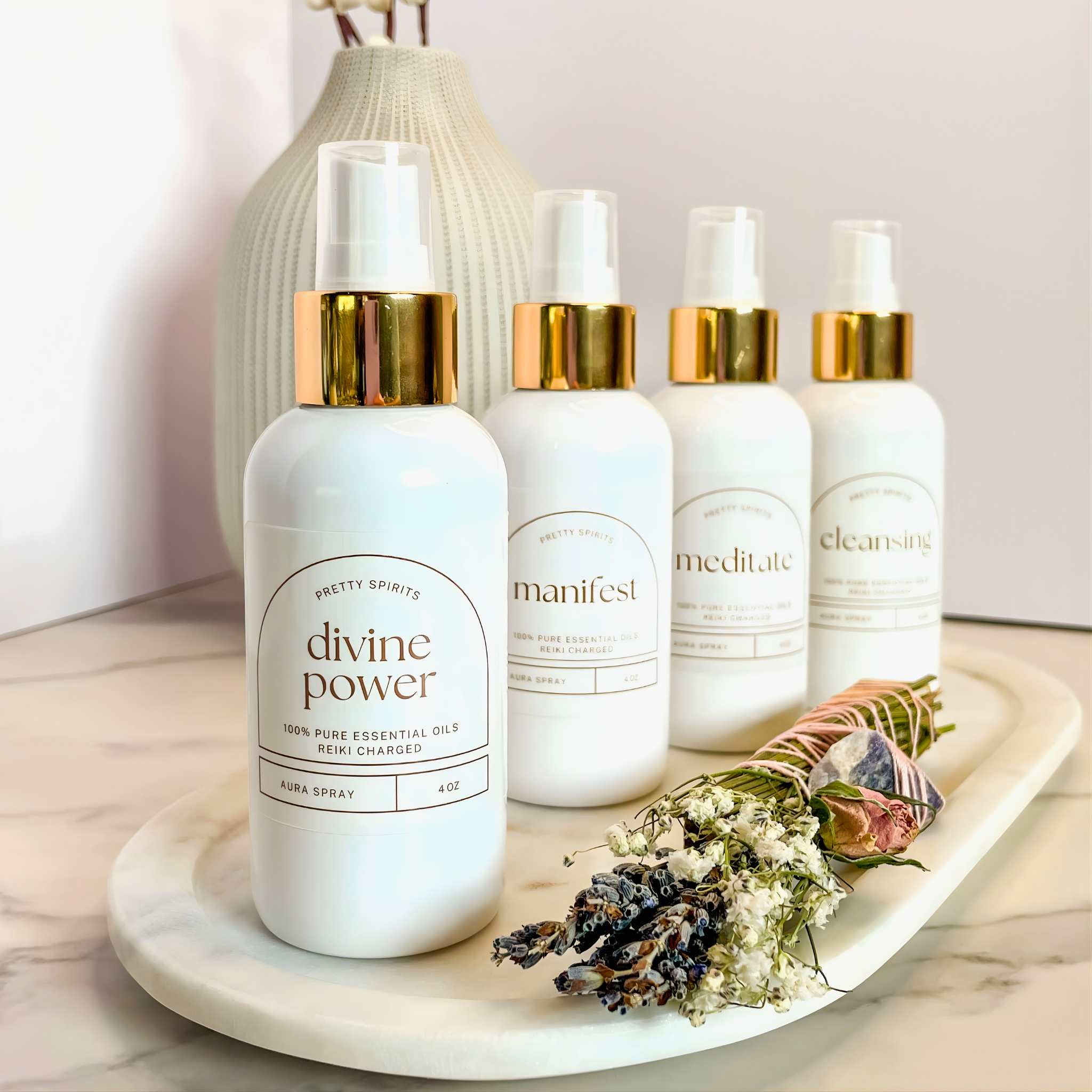 Set of white bottles with gold caps on a marble tray with flowers and a vase in the background.
