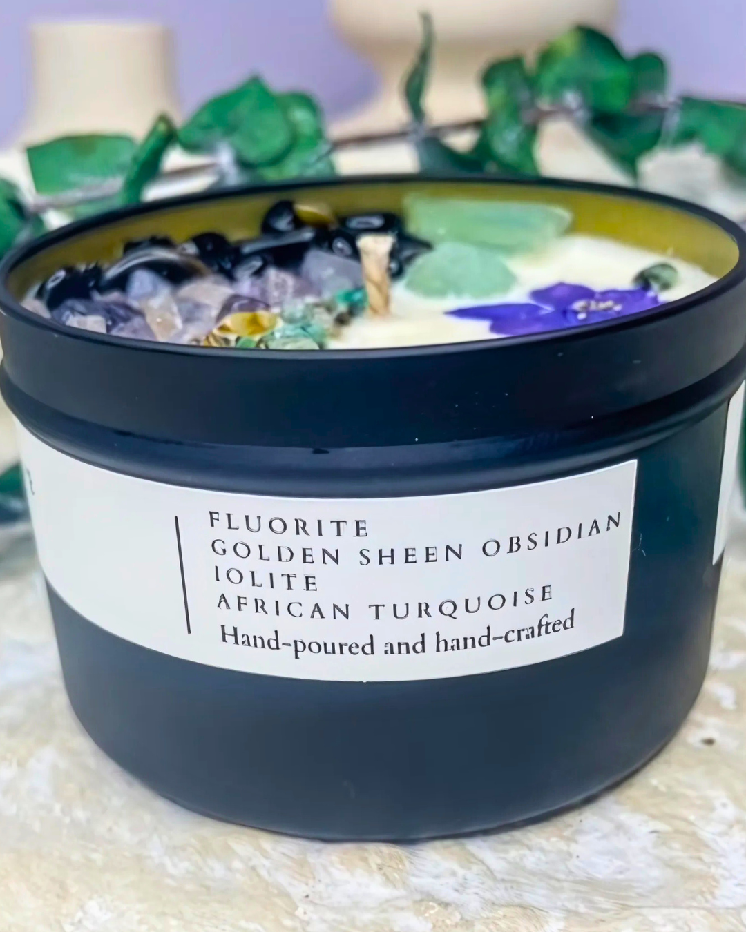 Candle with embedded stones and a label on a textured surface