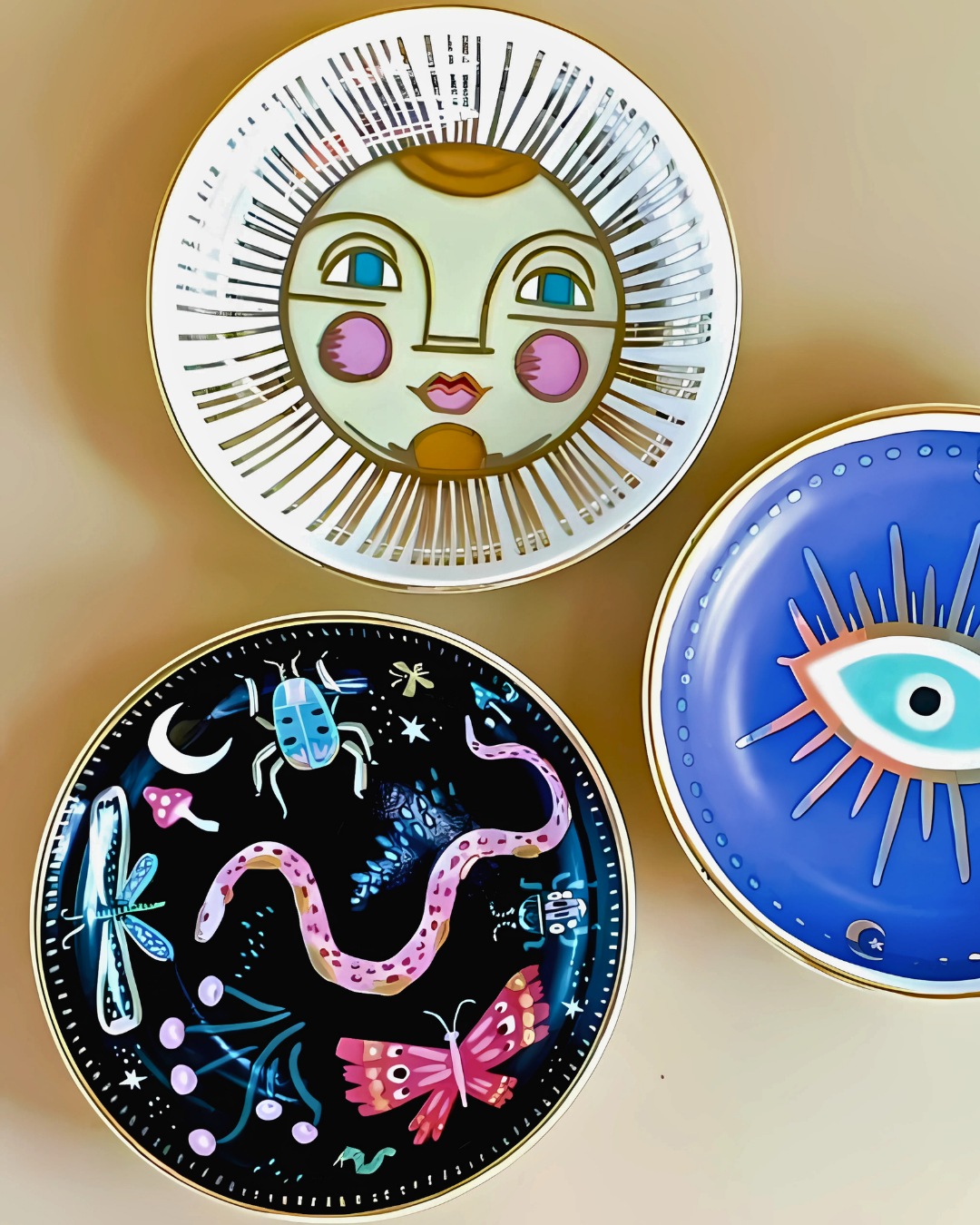 Three decorative plates with artistic designs on a beige background