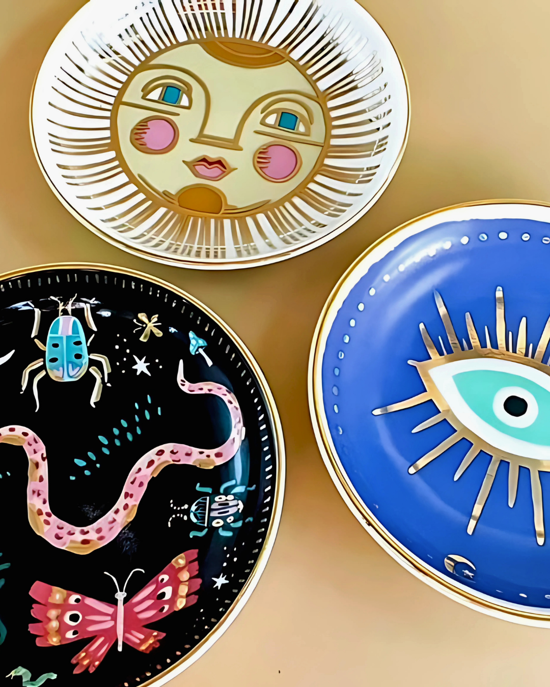 Three decorative plates with artistic designs on a beige background