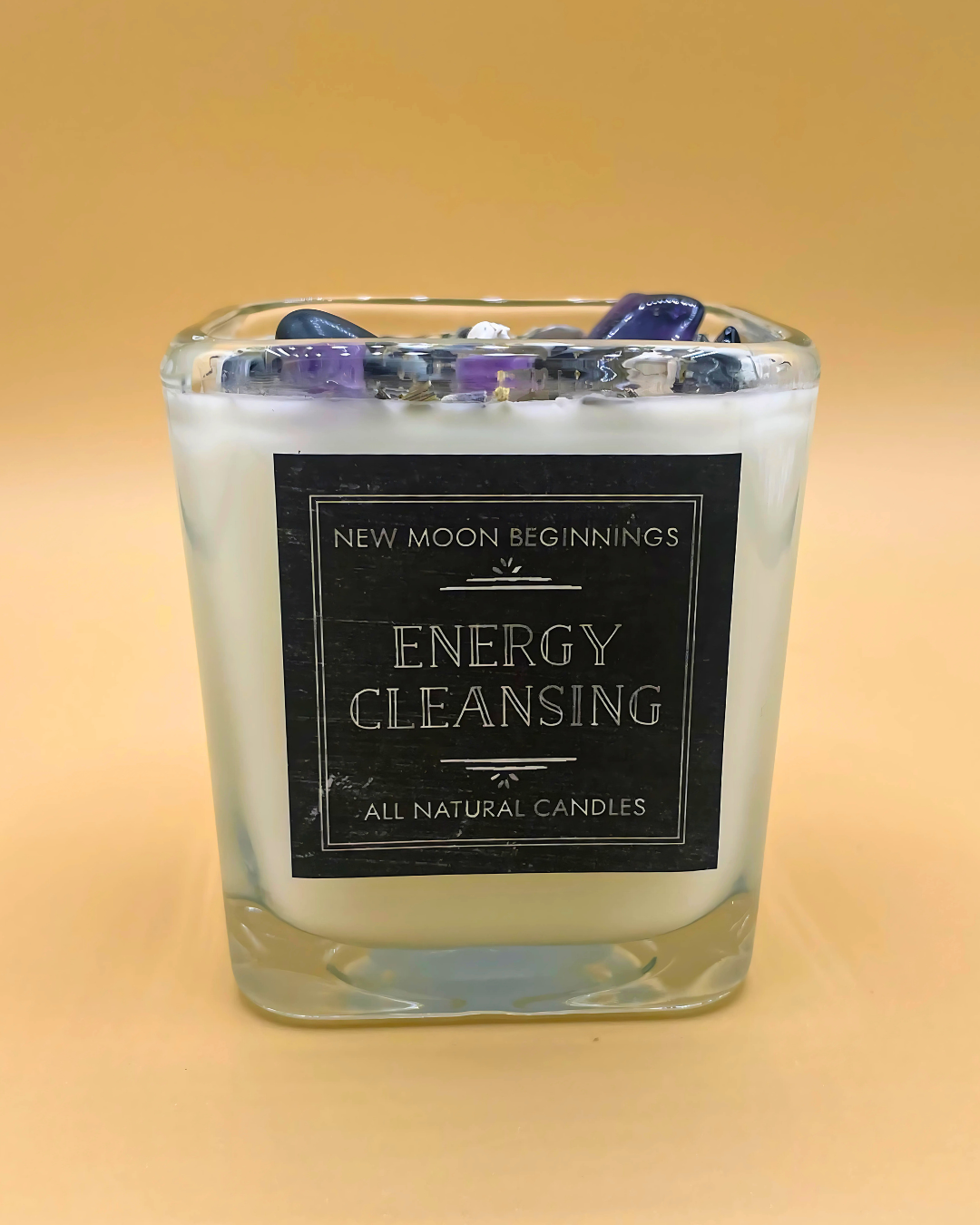 Candle labeled 'New Moon Beginnings Energy Cleansing' on a beige background