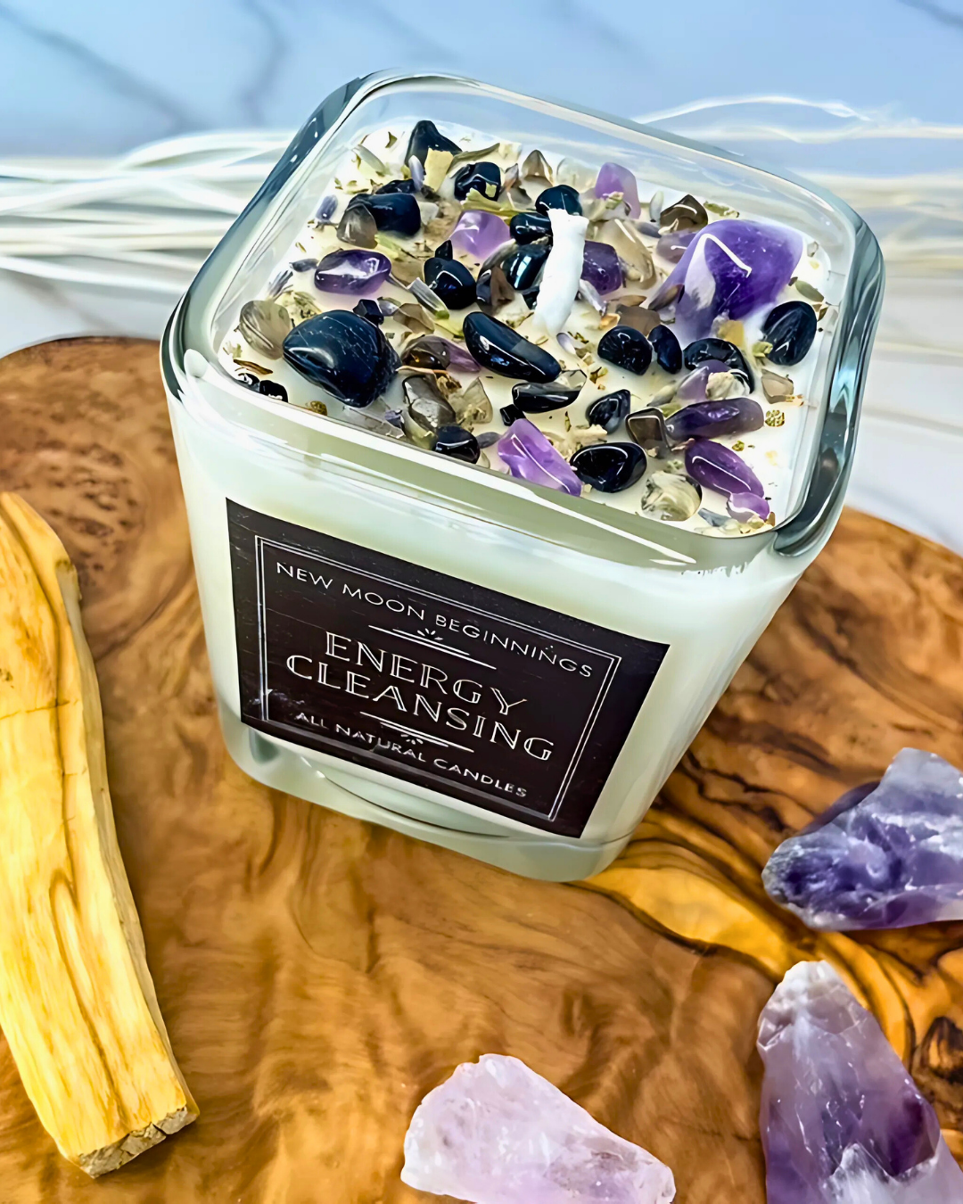 Candle labeled 'Energy Cleansing' with crystals on a wooden surface