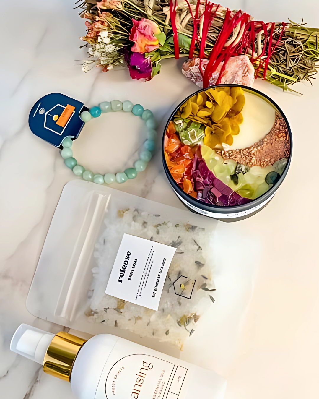 Colorful flower arrangement, bottle of skincare product, bracelet, and small bowl with flowers on a marble surface.