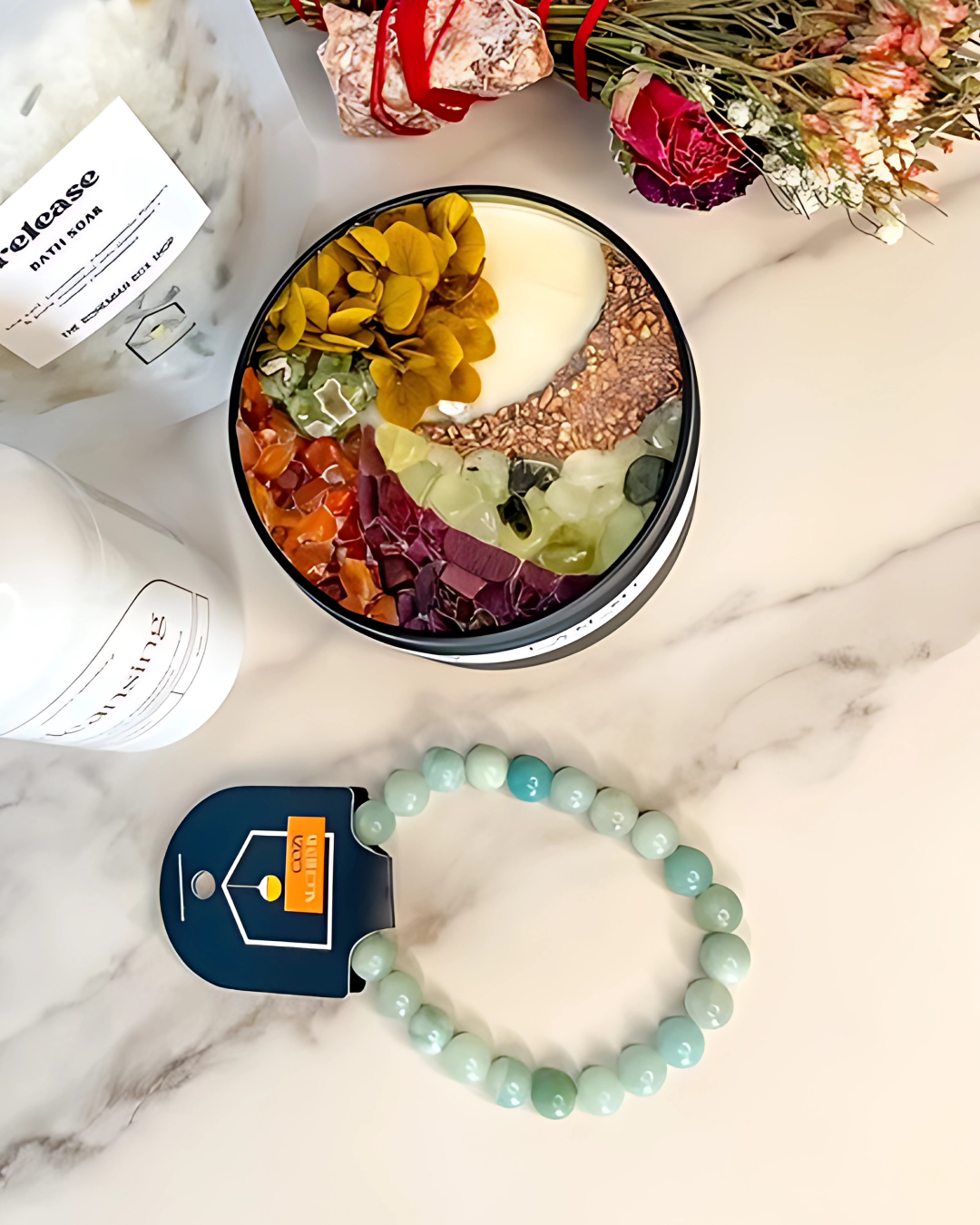 Colorful bowl with various items on a marble surface, featuring a bracelet and a product packaging.