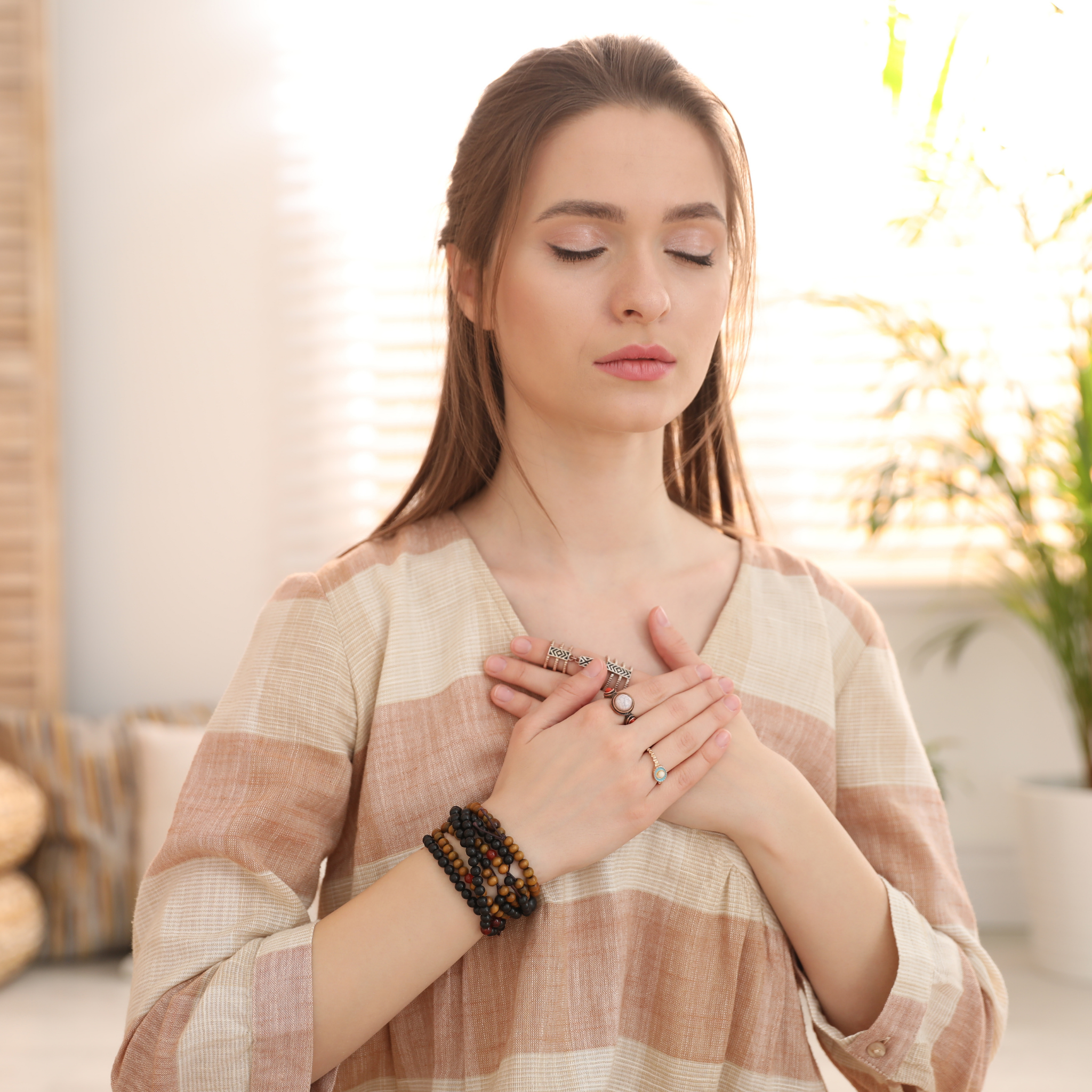 Woman in a striped shirt with hands over her heart in a warm indoor setting