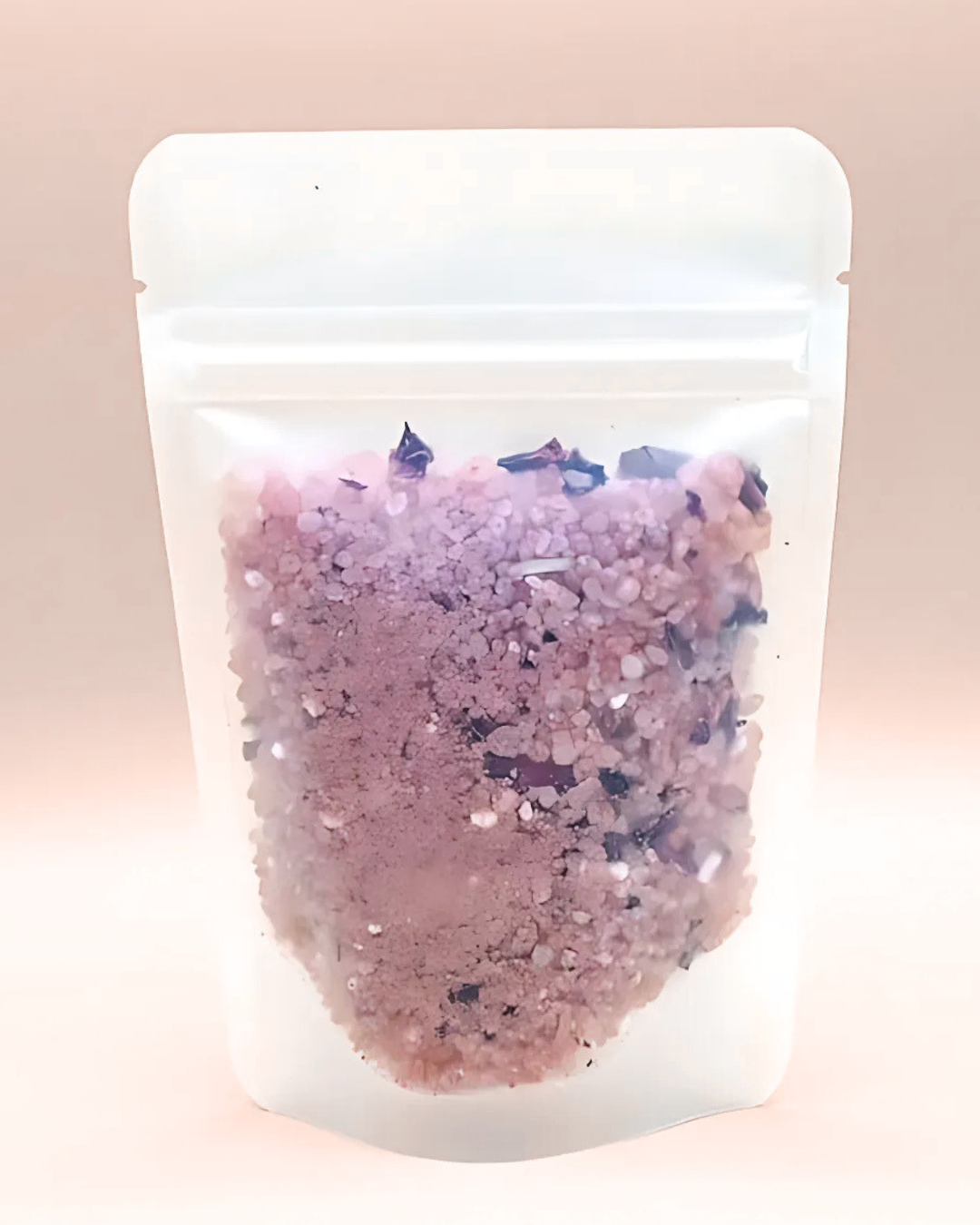 Pink bath salts in a clear plastic bag on a light pink background