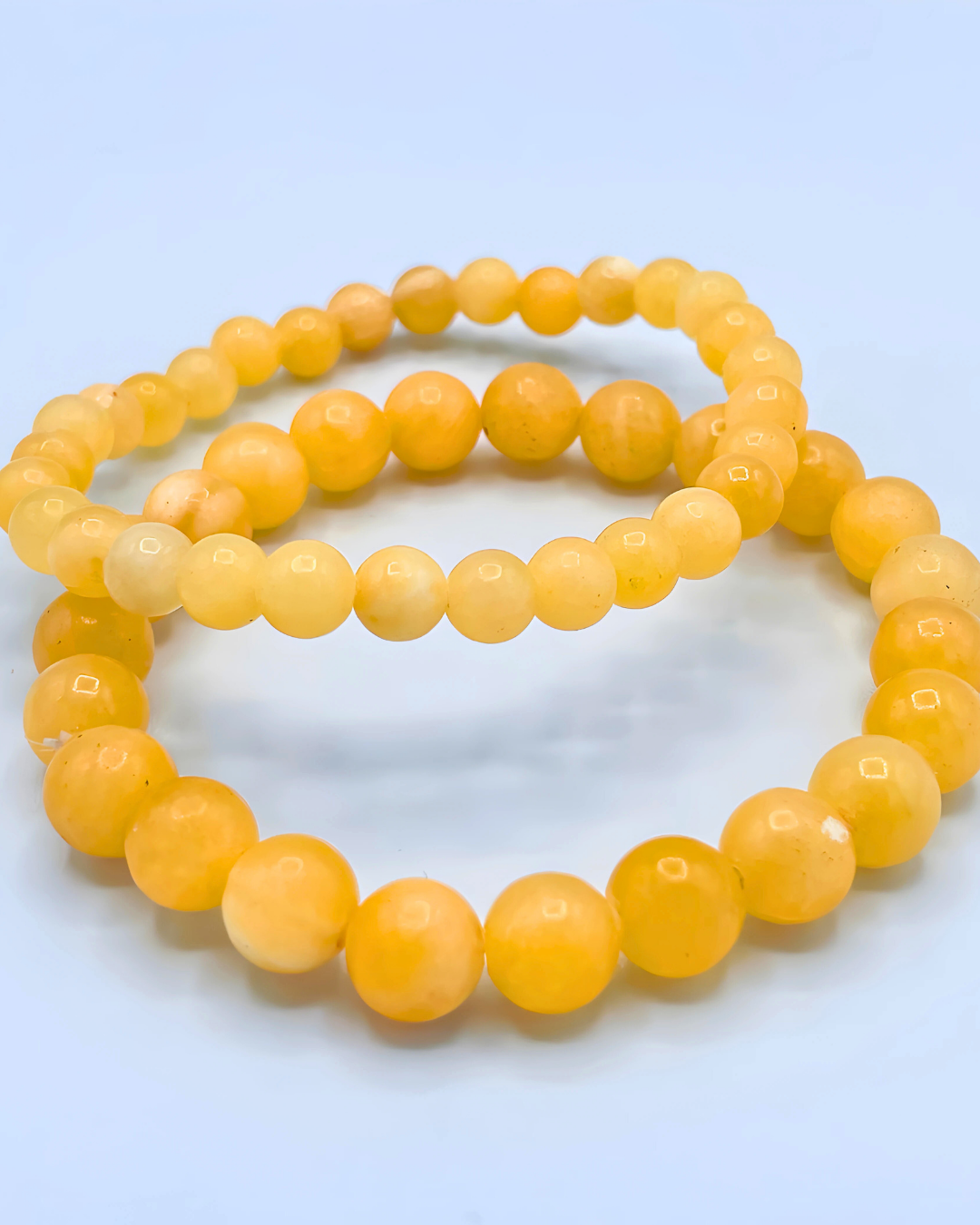 Two yellow beaded bracelets on a light blue background