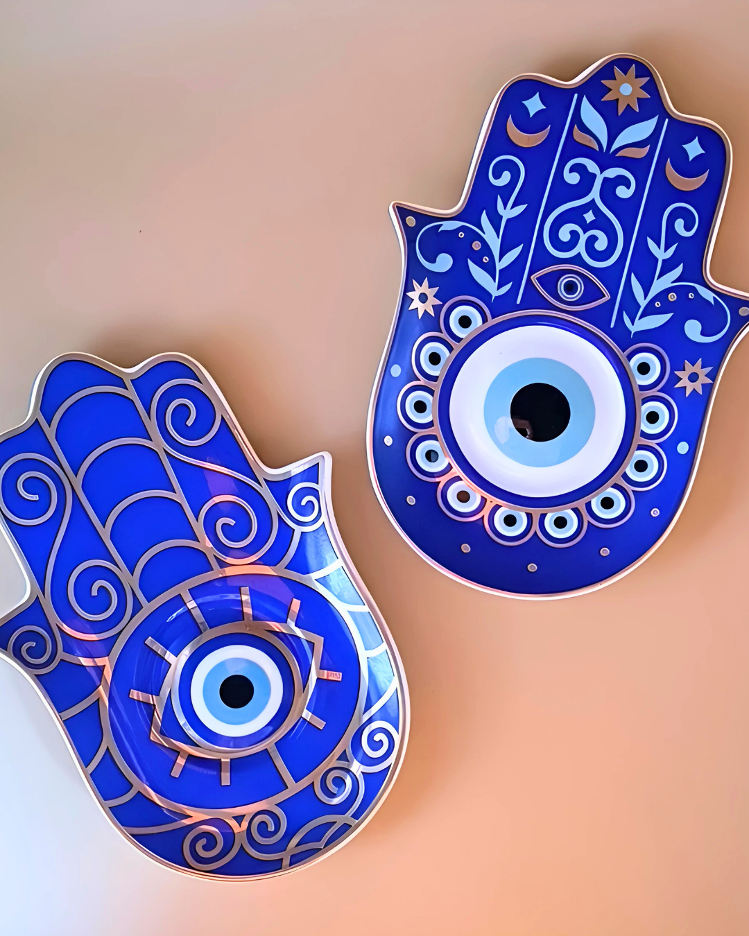 Two blue Hamsa hand decorations with eye design on a beige background