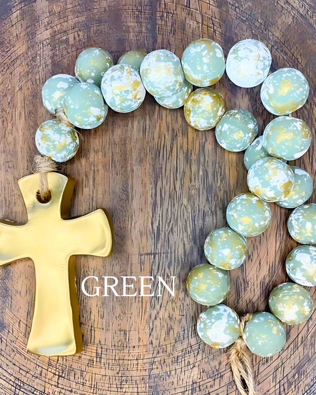 Decorative wreath with gold cross and green marbled stones on a wooden background