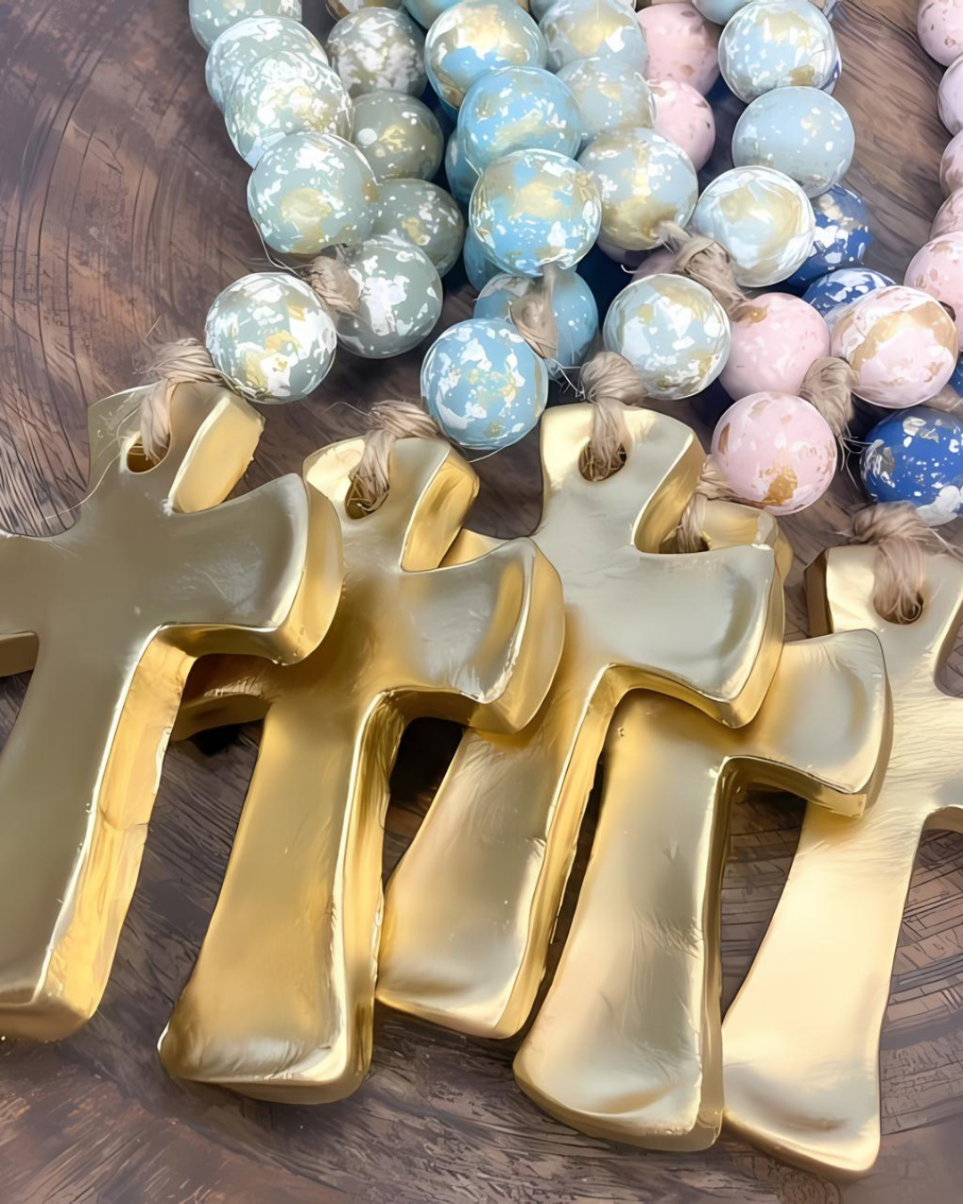 Gold crosses on a wooden surface with colorful beads in the background