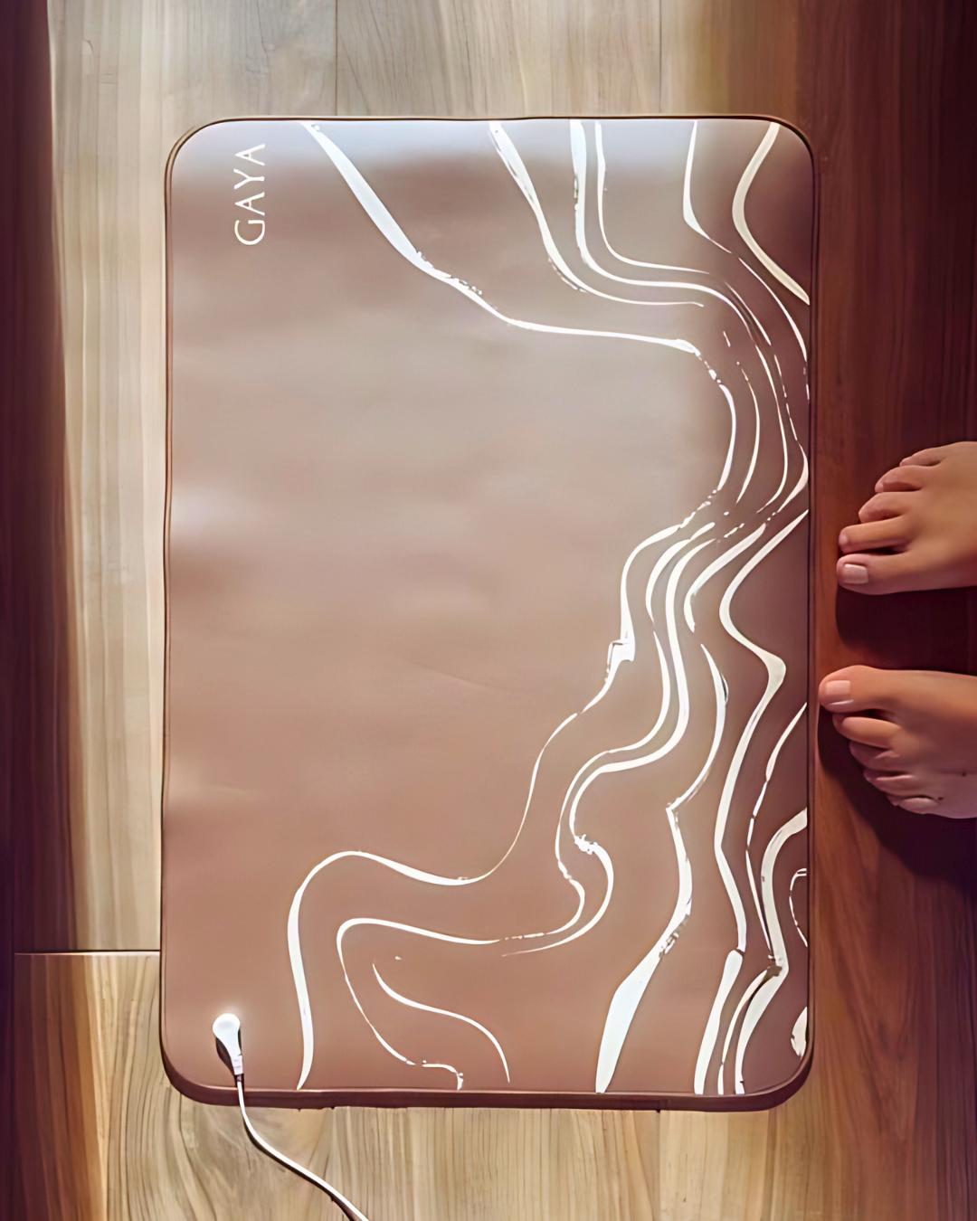 GAYA heating pad on a wooden floor with a person's foot near it