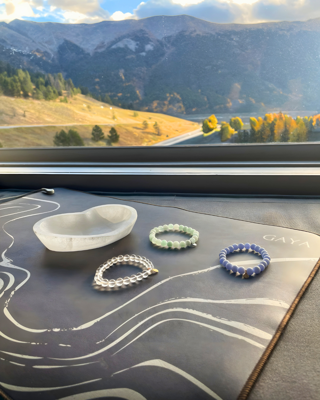 Bracelets on a car dashboard with a scenic mountain view outside