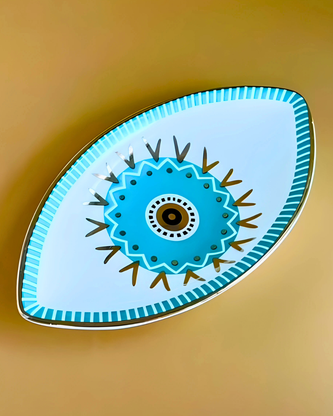 Decorative eye-shaped object with blue floral design on a gold background