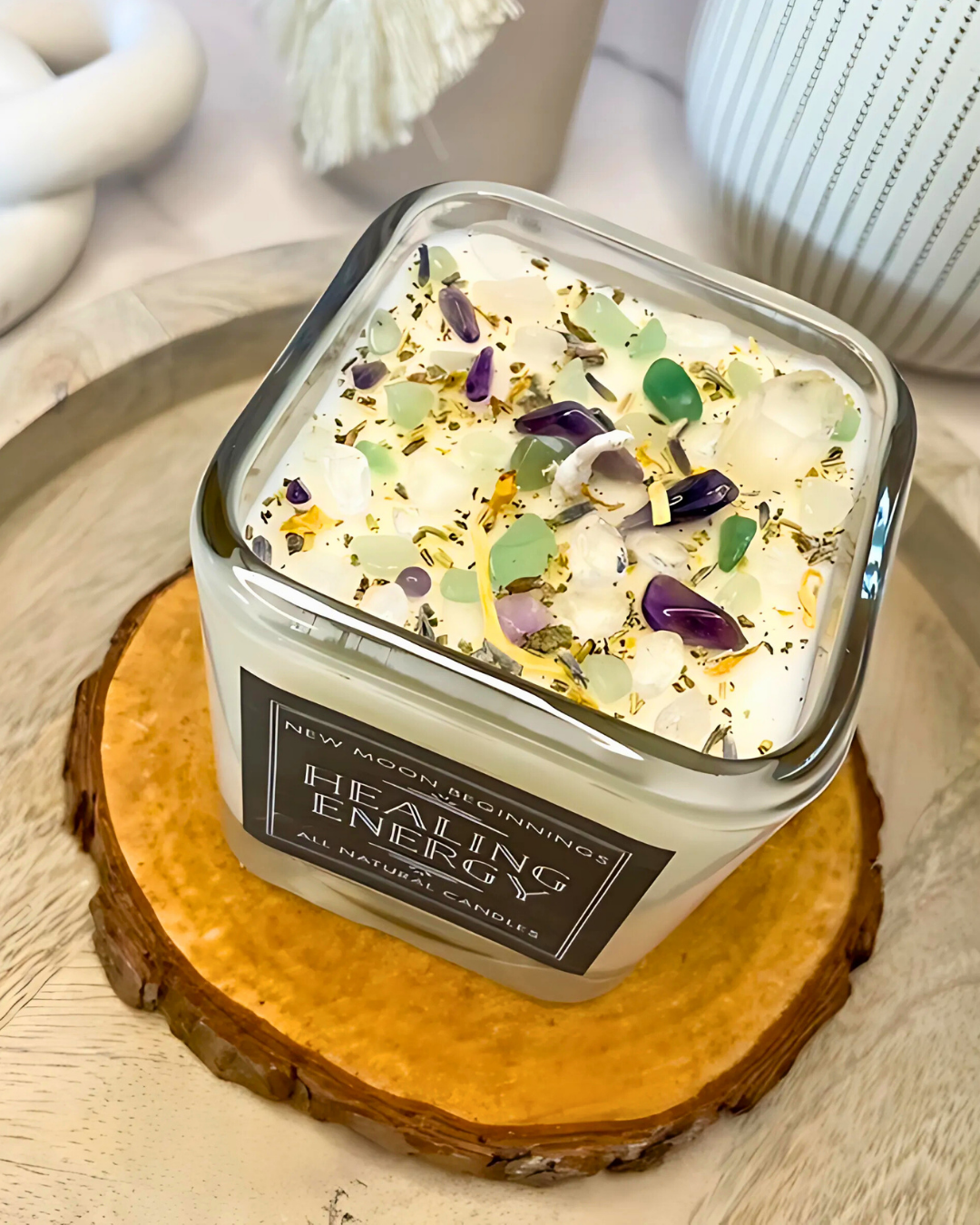 Candle labeled 'New Moon Remedies' on a wooden coaster with decorative elements.