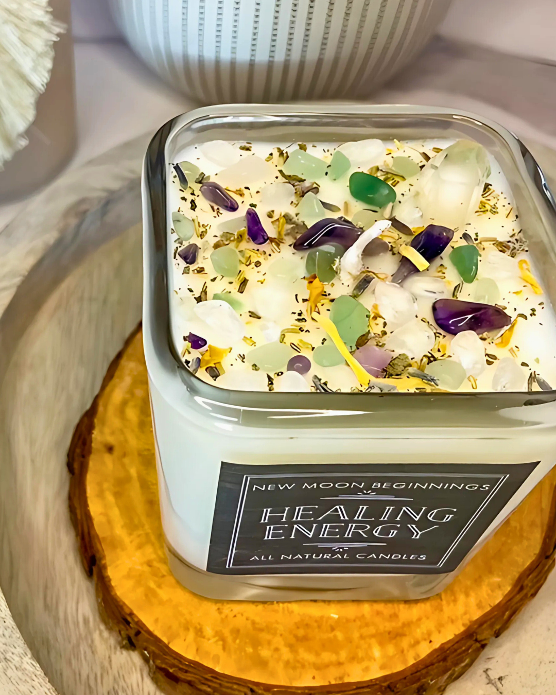 Candle labeled 'Healing Energy' with decorative elements on a wooden coaster.