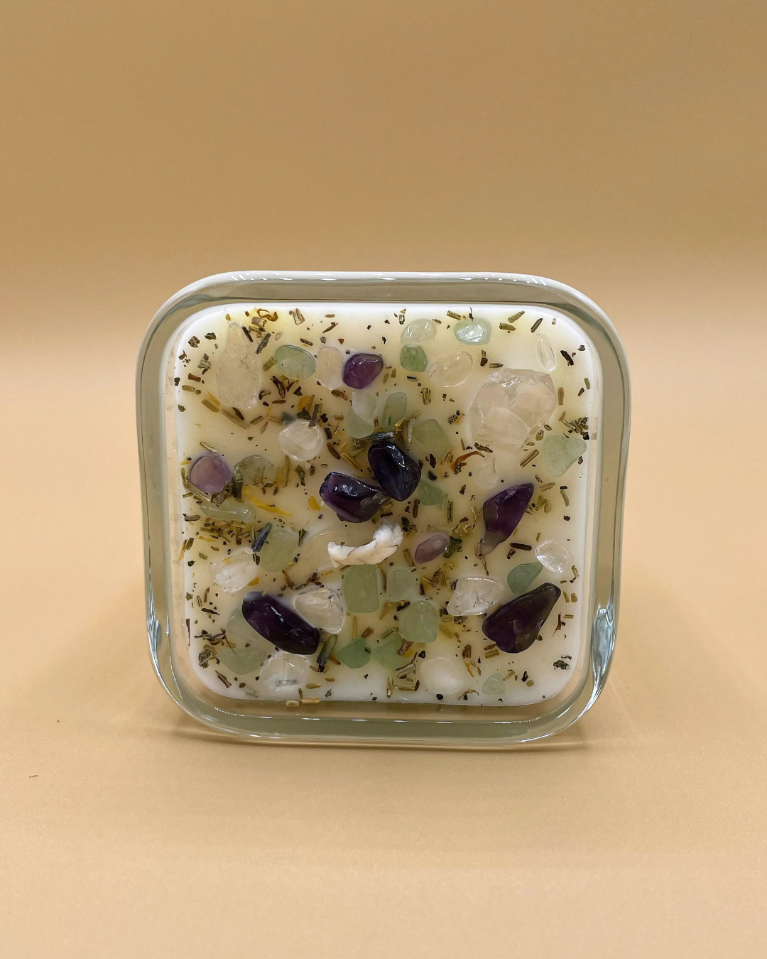 Square glass container with embedded stones on a beige background