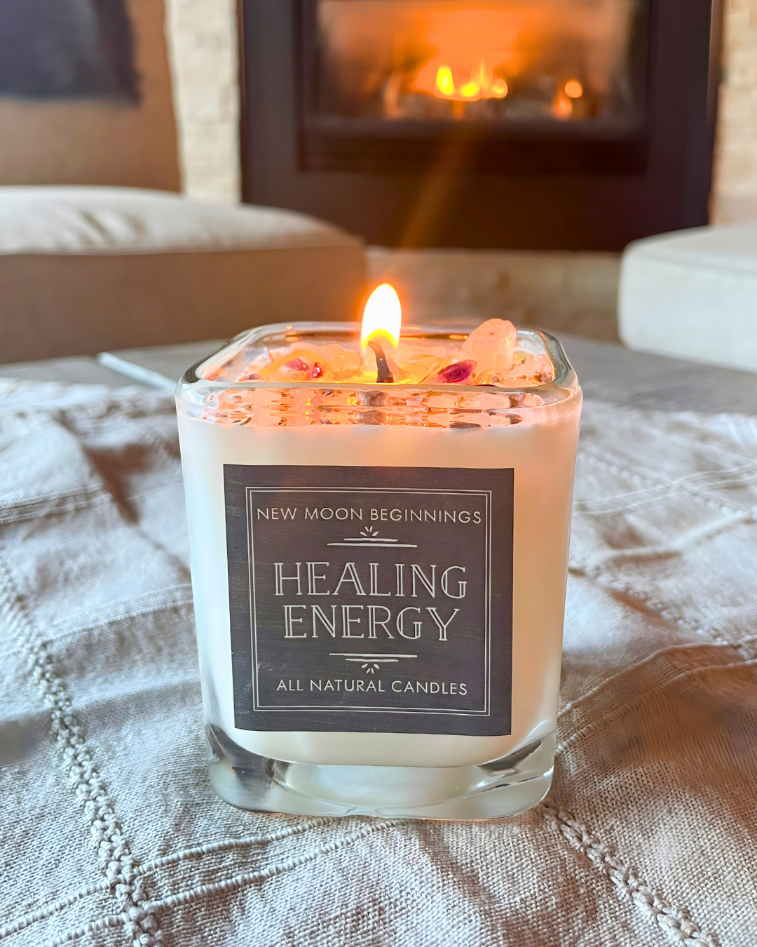 Candle labeled 'Healing Energy' on a textured surface with a fireplace in the background