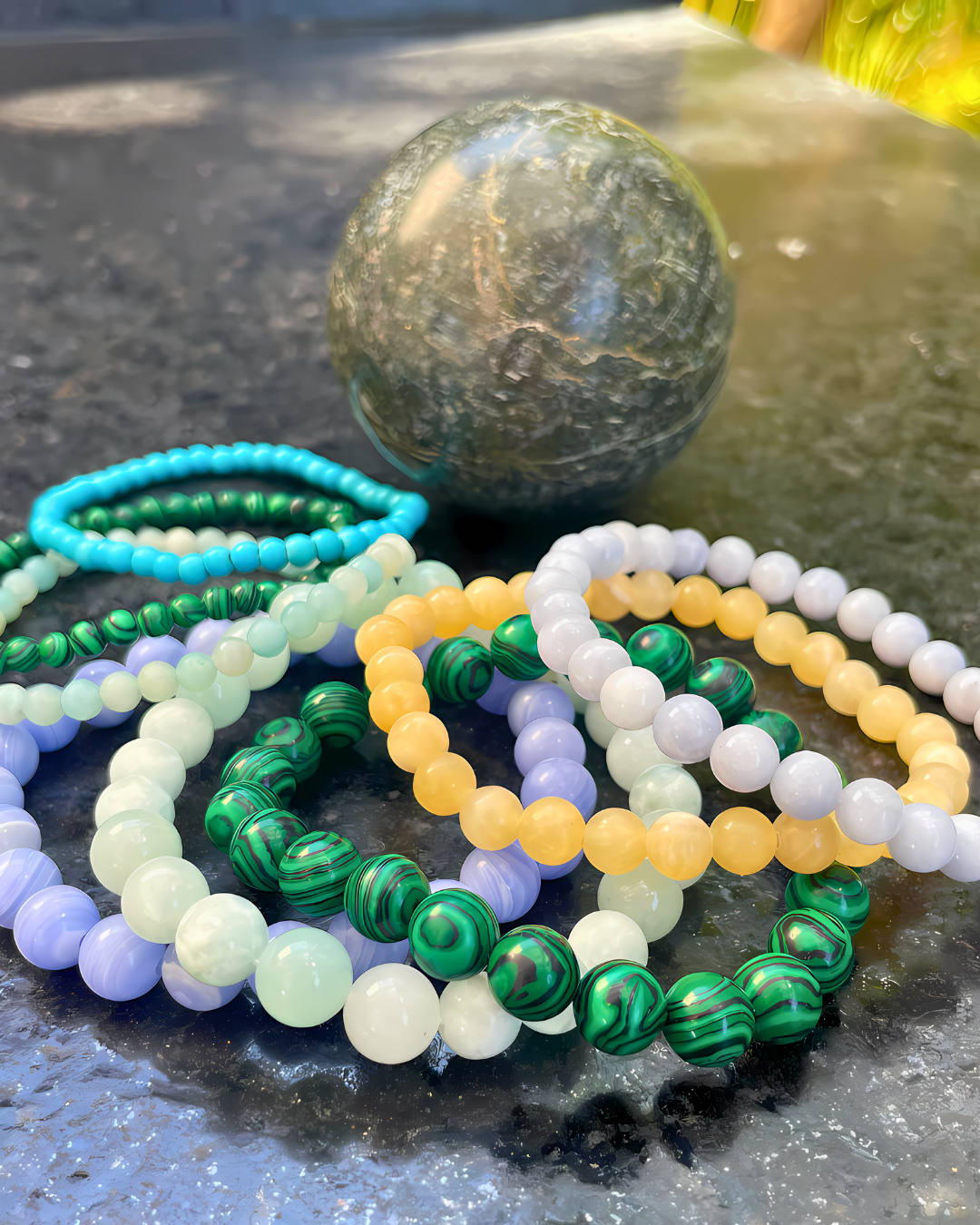 Colorful beaded bracelets on a dark surface with a marble-like stone.