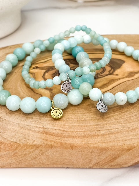 Three turquoise beaded bracelets with charms on a wooden surface