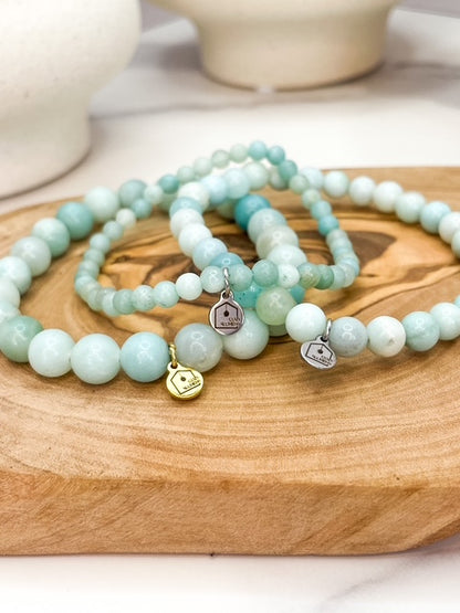 Set of light blue beaded bracelets with charms on a wooden surface