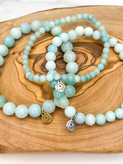 Set of light blue beaded bracelets with charms on a wooden surface
