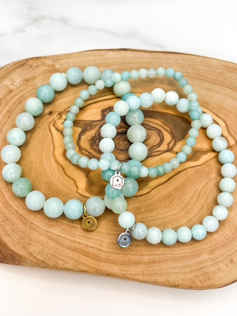 Set of light blue amazonite beaded bracelets with charms on a wooden surface