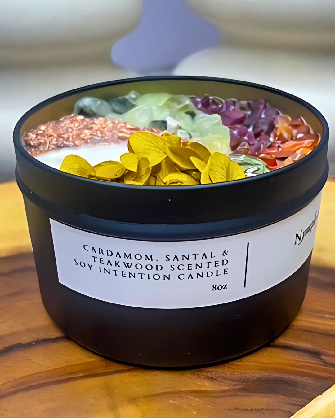 Scented candle with colorful dried flowers on a wooden surface
