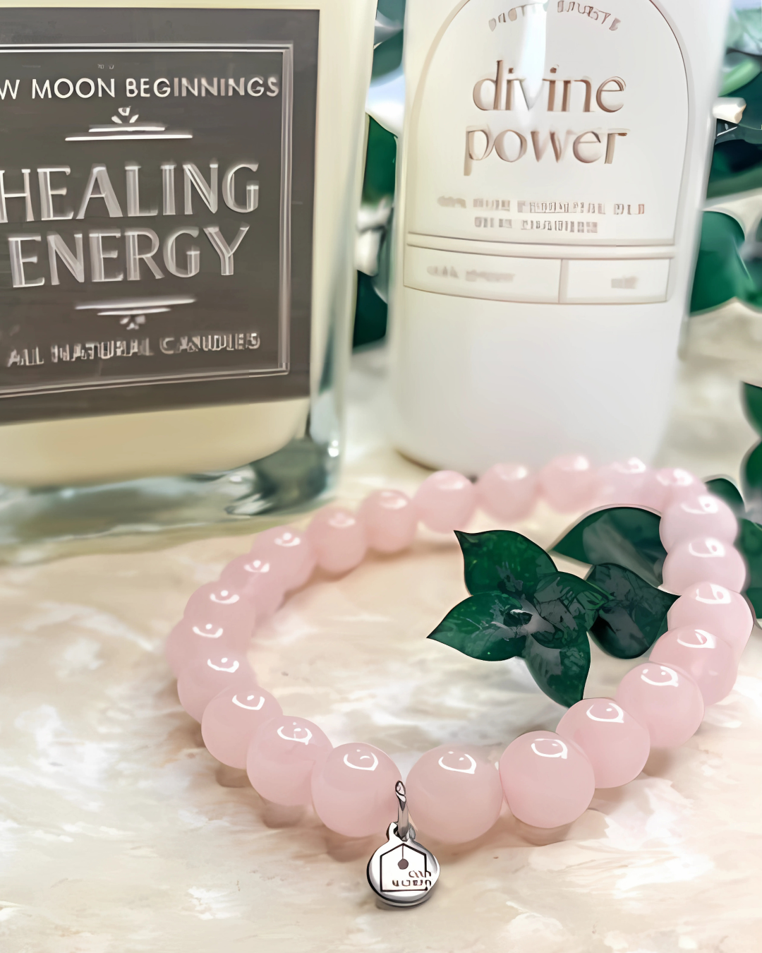 Pink beaded bracelet with a silver charm on a textured surface with candles in the background.
