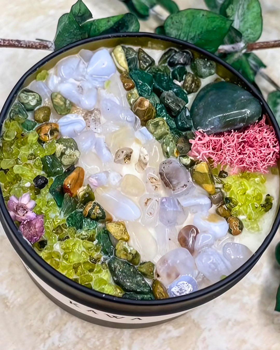 Decorative bowl with multicolored stones and plants on a textured surface