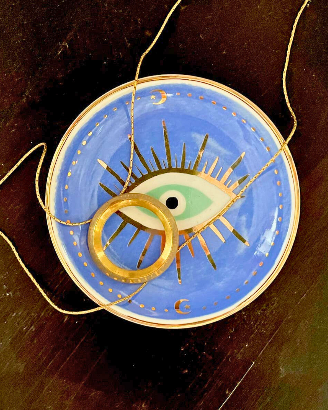 Decorative plate with an eye design on a wooden surface